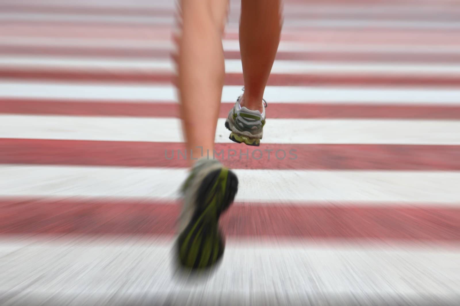 City Running. Closeup of woman running shoes in action on crosswalk in urban setting. Zoom blurred effect with shallow depth of field with focus on right running shoe.