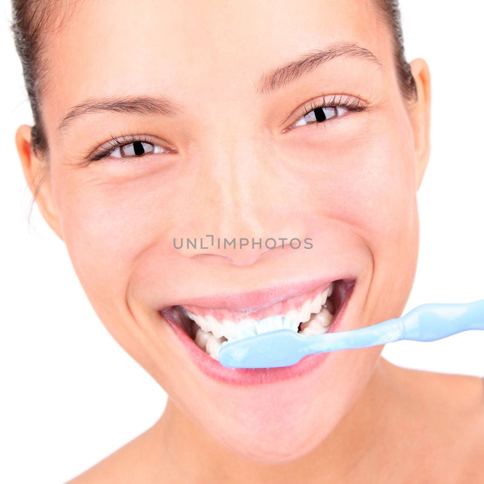 Brushing teeth. Closeup of woman brushing her teeth with toothpaste and a manual toothbrush. Beautiful mixed race asian / caucasian model.