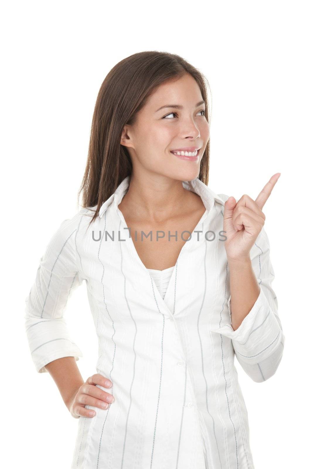 Woman pointing and looking to the side. Casual young businesswoman in white shirt looking, pointing and smiling at copy space. Beautiful young mixed race chinese / caucasian isolated on seamless white background. 