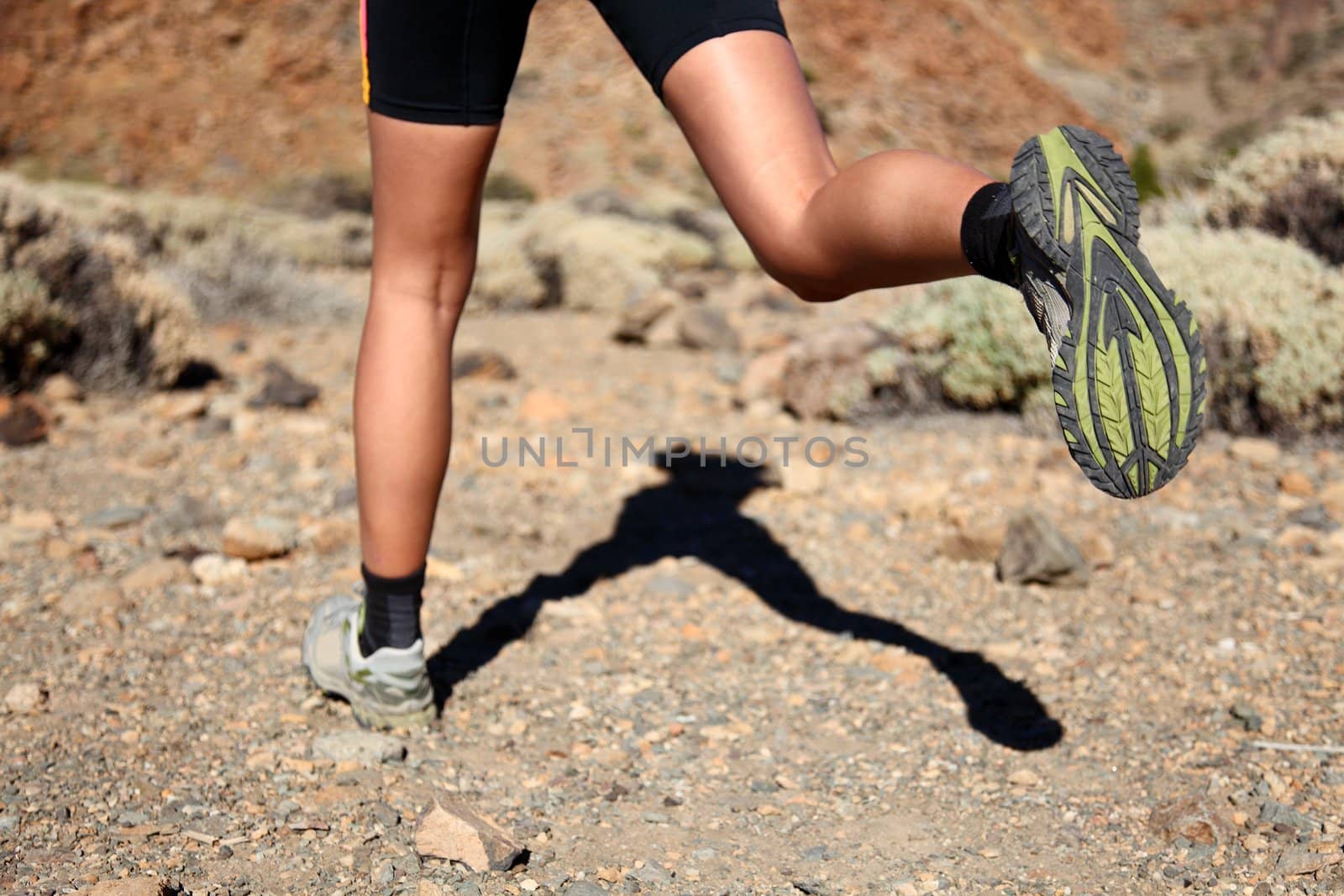 Woman running on trail. Closeup of woman trail running in desert on the volcano Teide, Tenerife. 