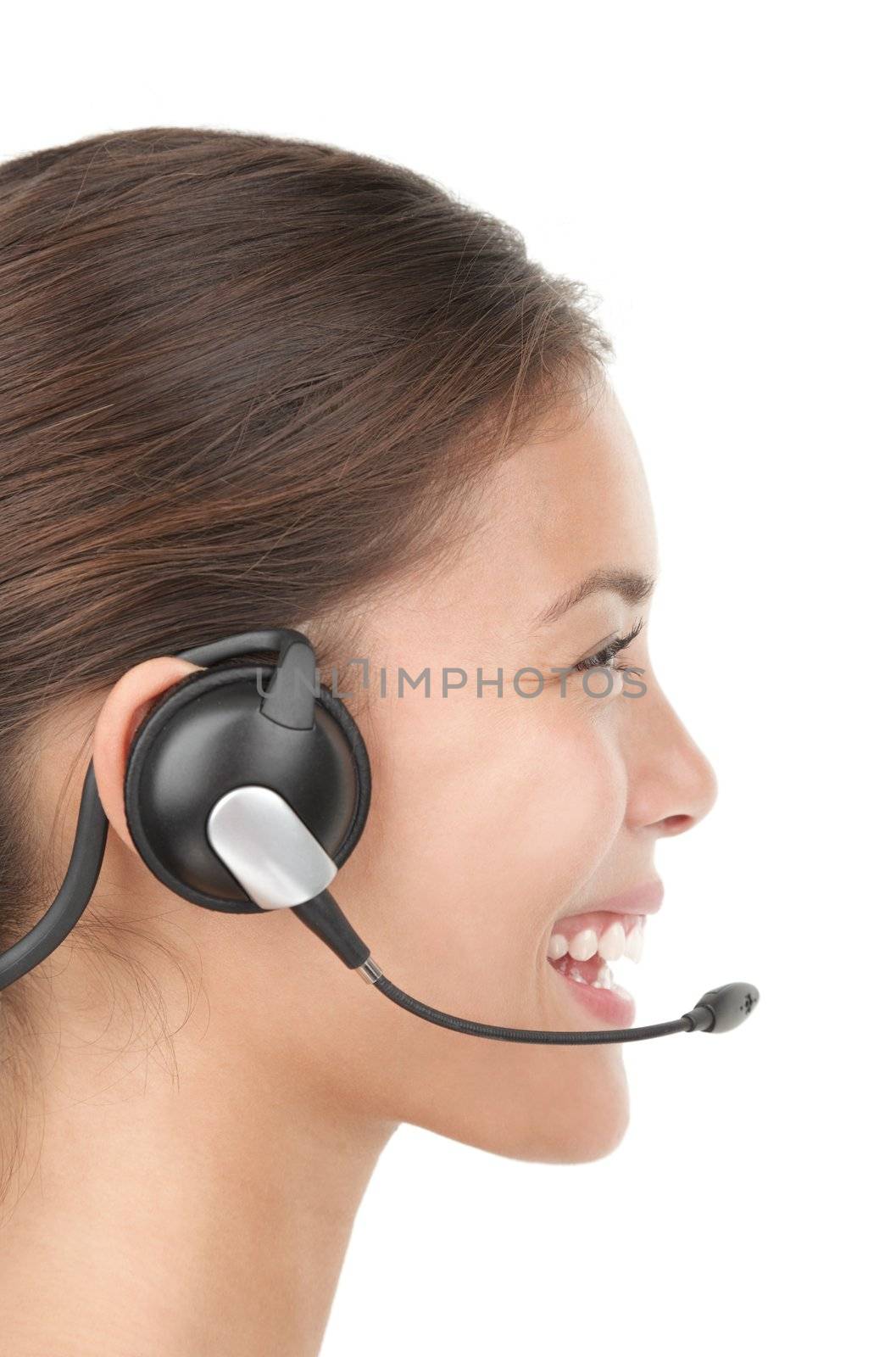 Headset woman in profile - smiling very kindly. Closeup of beautiful young mixed race chinese / caucasian secretary / assistant speaking with headphones while working in call center. Isolated on seamless white background.