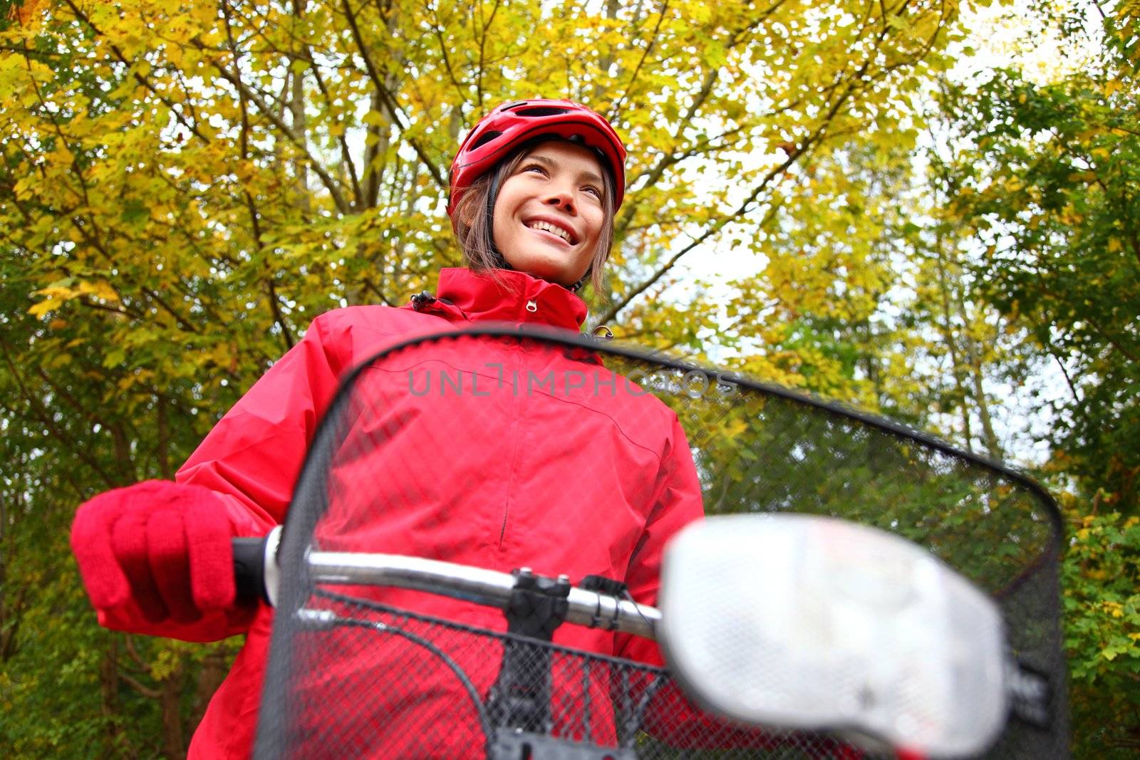 Biking. Woman in red on bike in autumn forest.