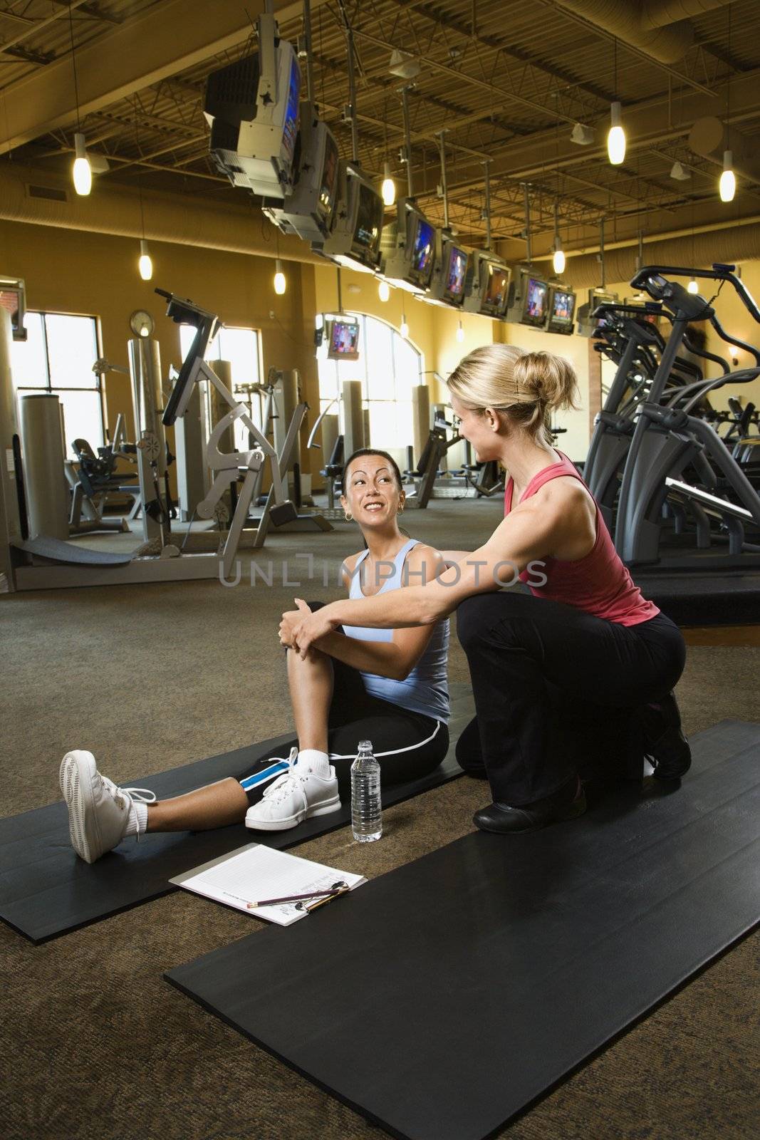 Prime adult Caucasian female with personal trainer at gym.