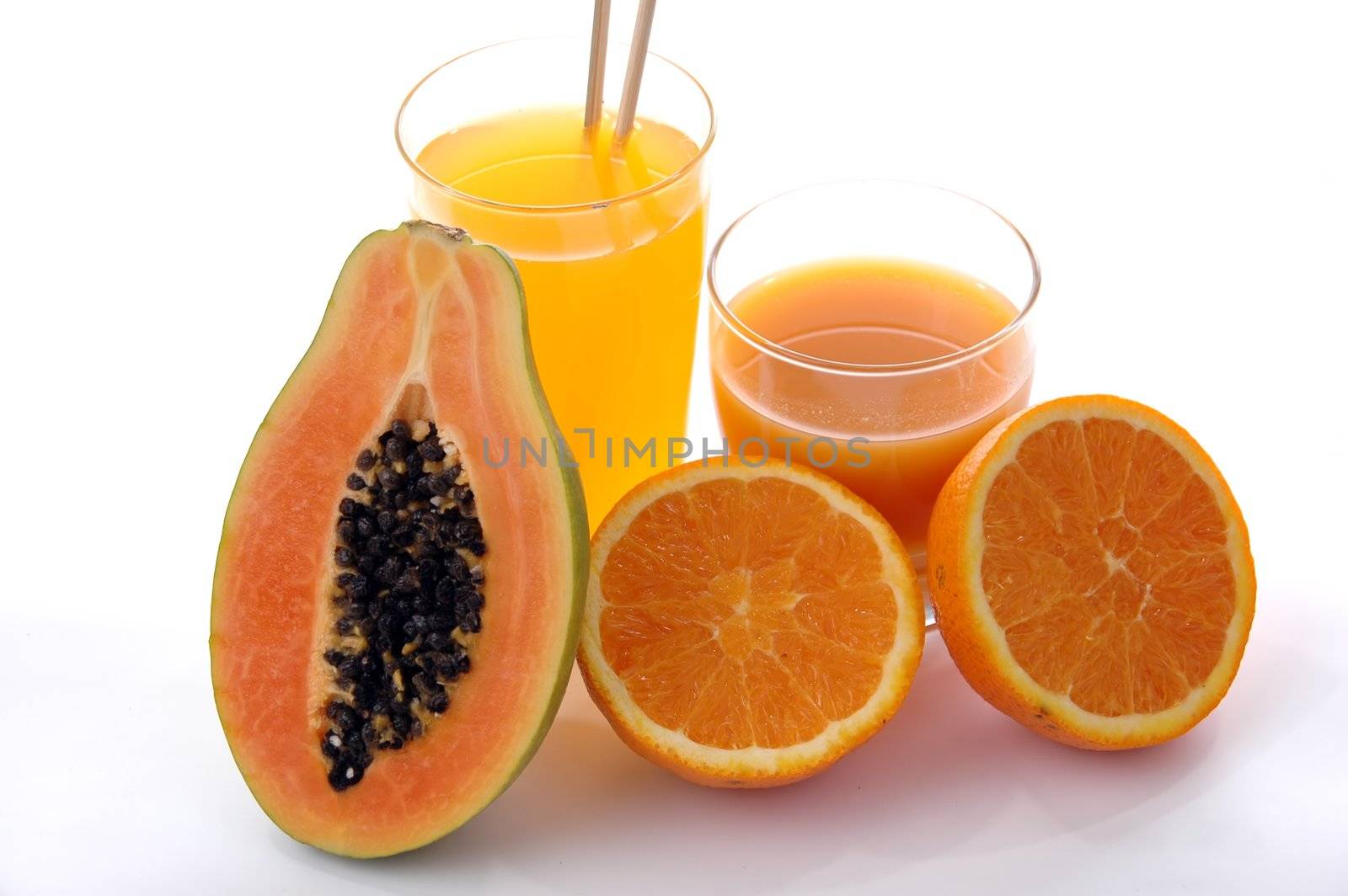 a glass of orange juice with cut oranges and papaya