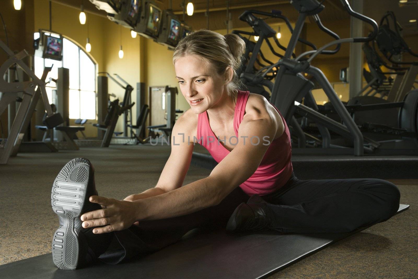 Woman stretching at gym. by iofoto