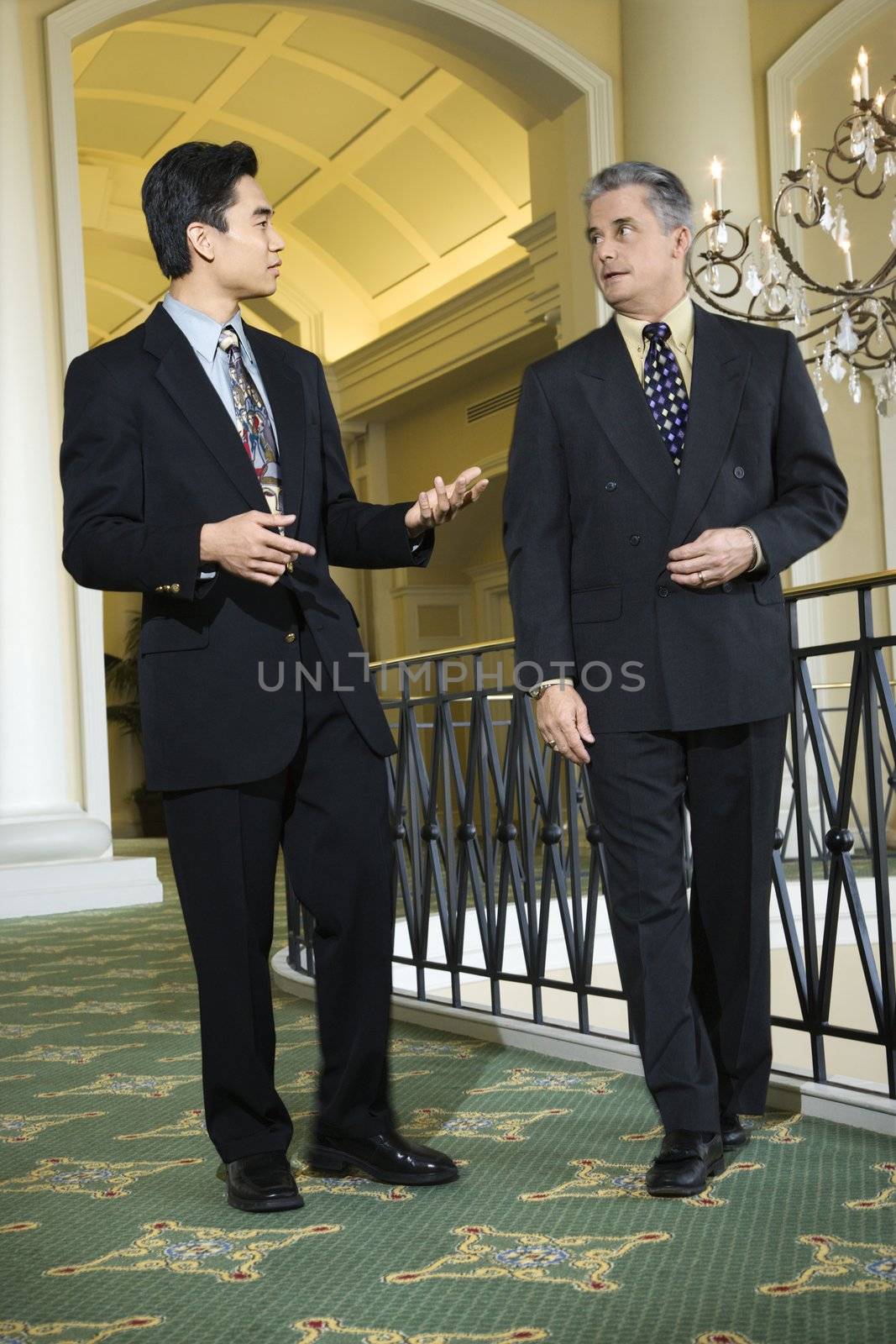 Caucasian prime adult male businessman and Asian prime adult male businessman in hotel.