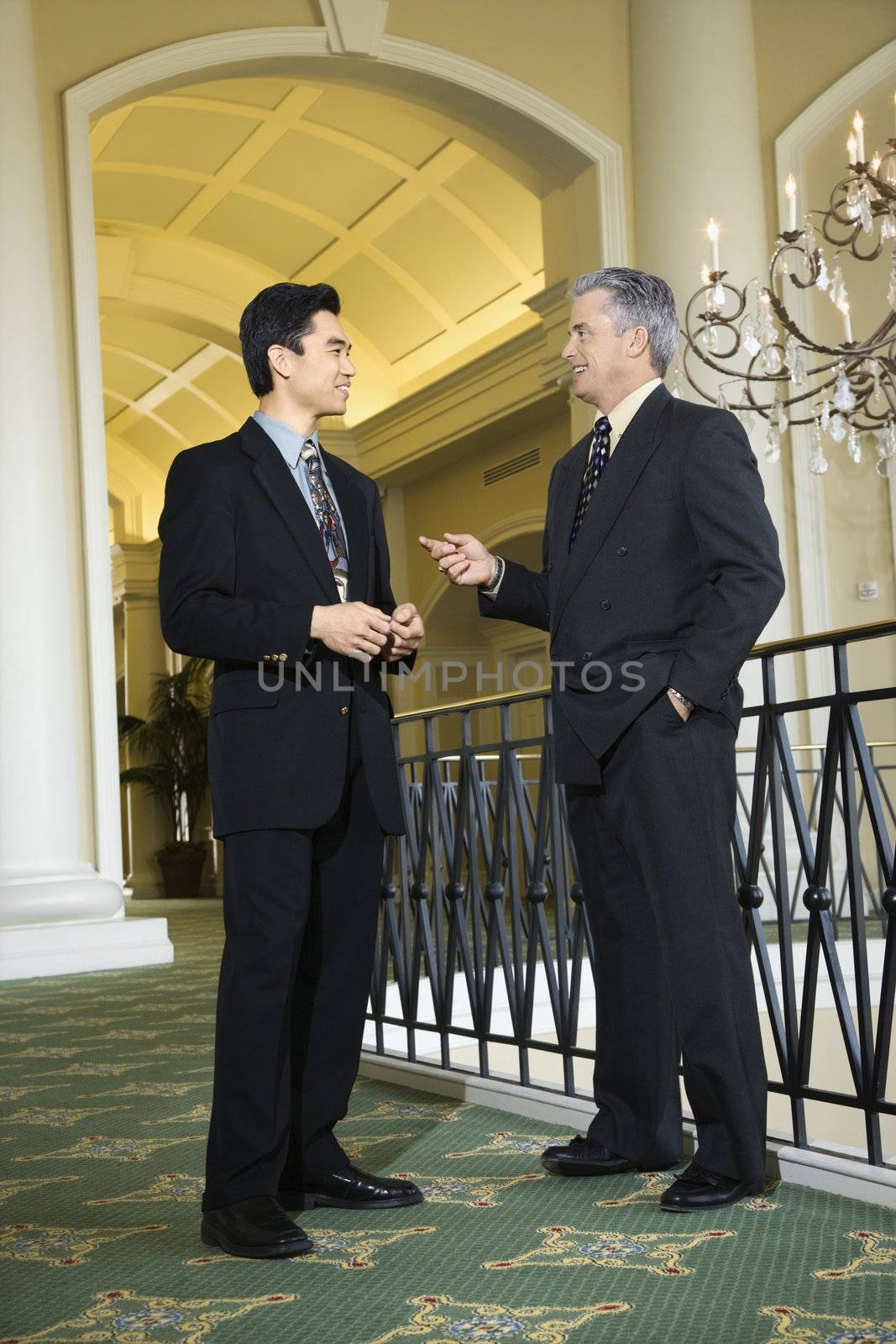 Caucasian prime adult male businessman and Asian prime adult male businessman in hotel.