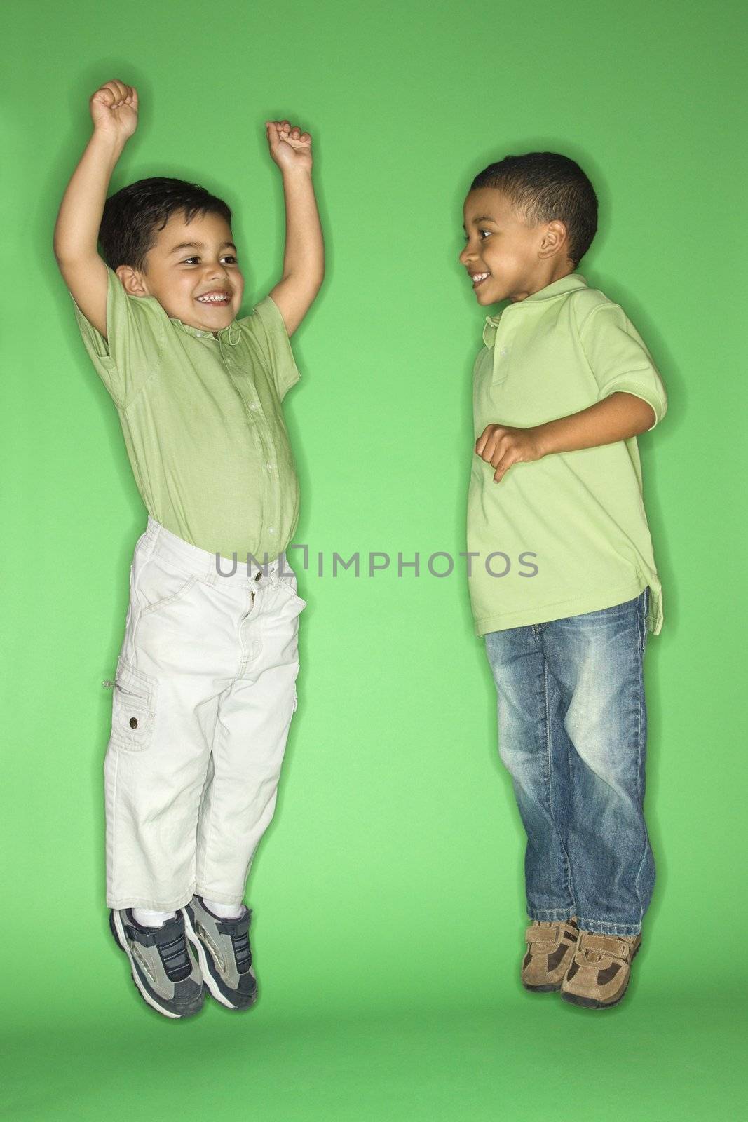 Hispanic and African American male child jumping.