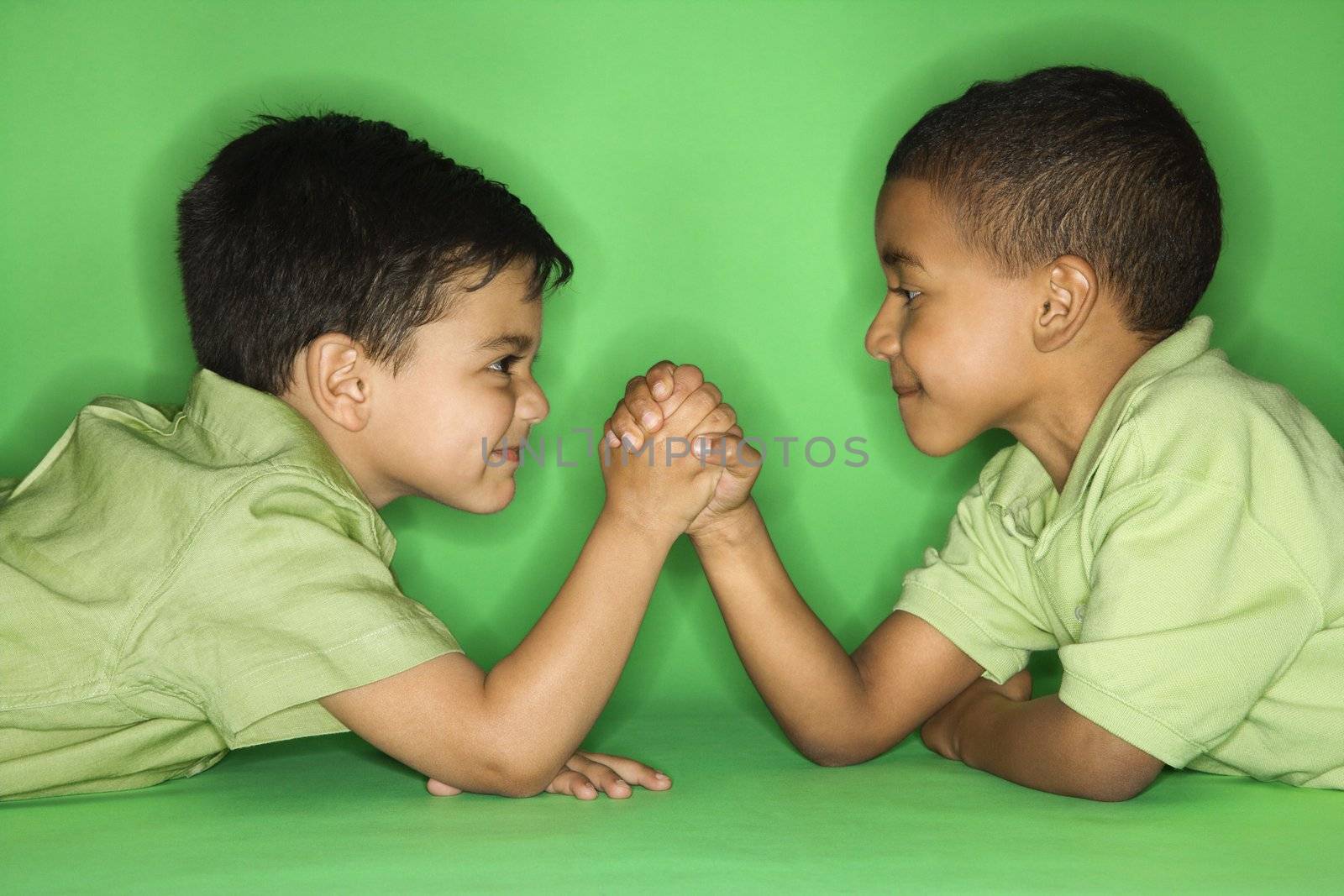 Hispanic and African American male child arm wrestling.