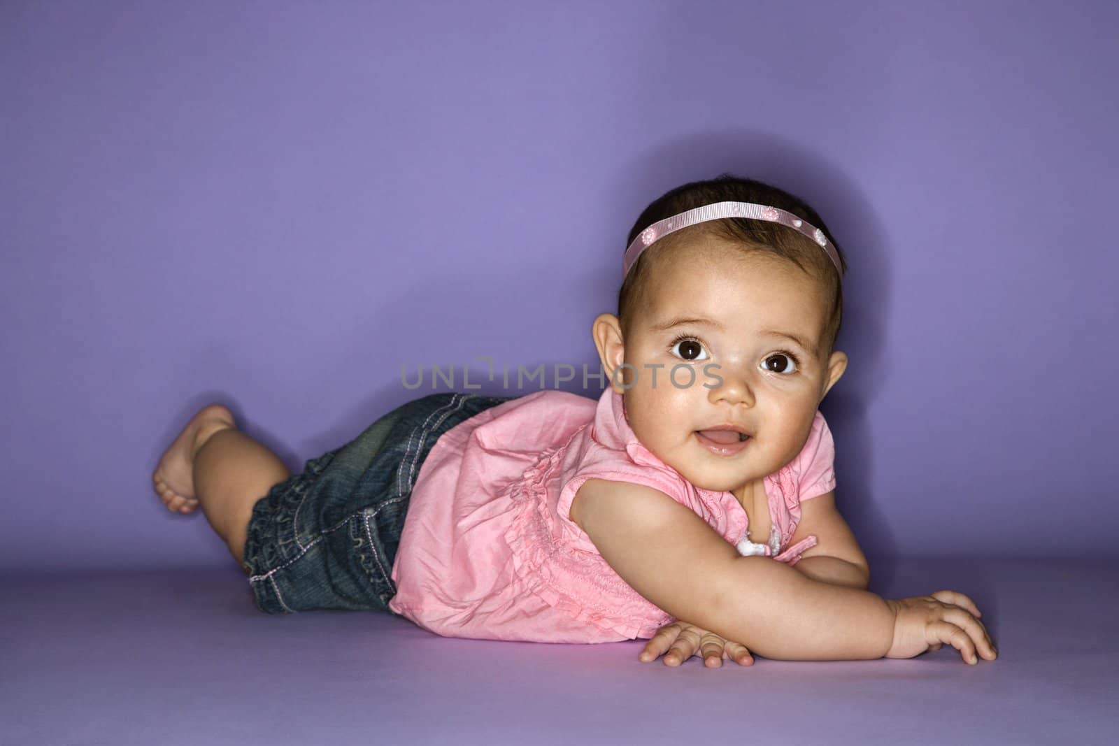 Hispanic female baby lying on stomach.