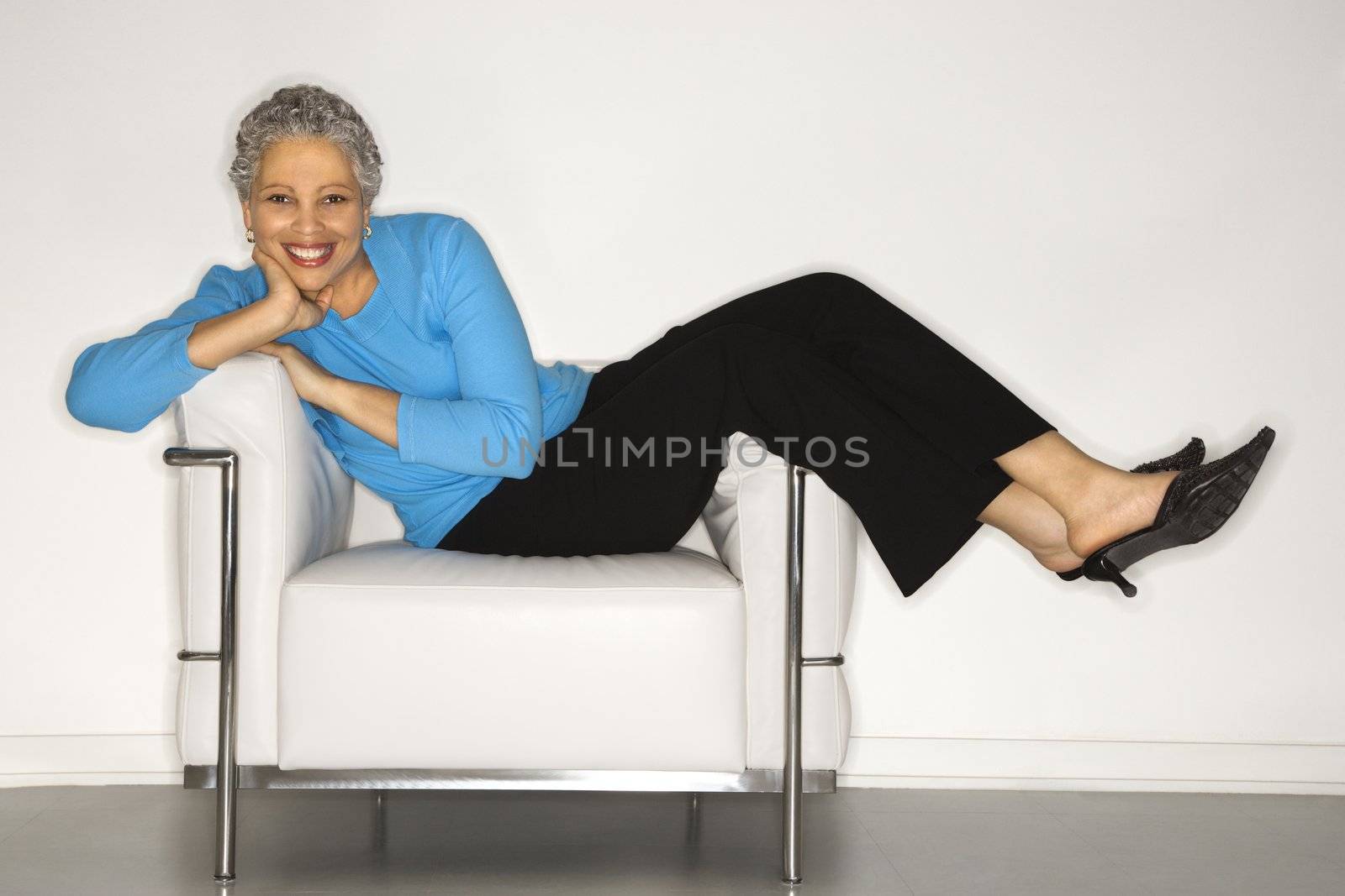 Woman lying back on chair. by iofoto