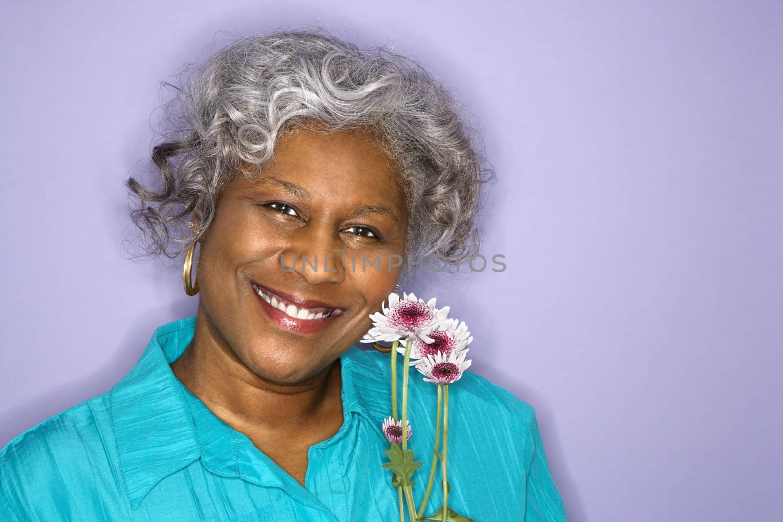 Mature adult African American female holding flowers smiling.