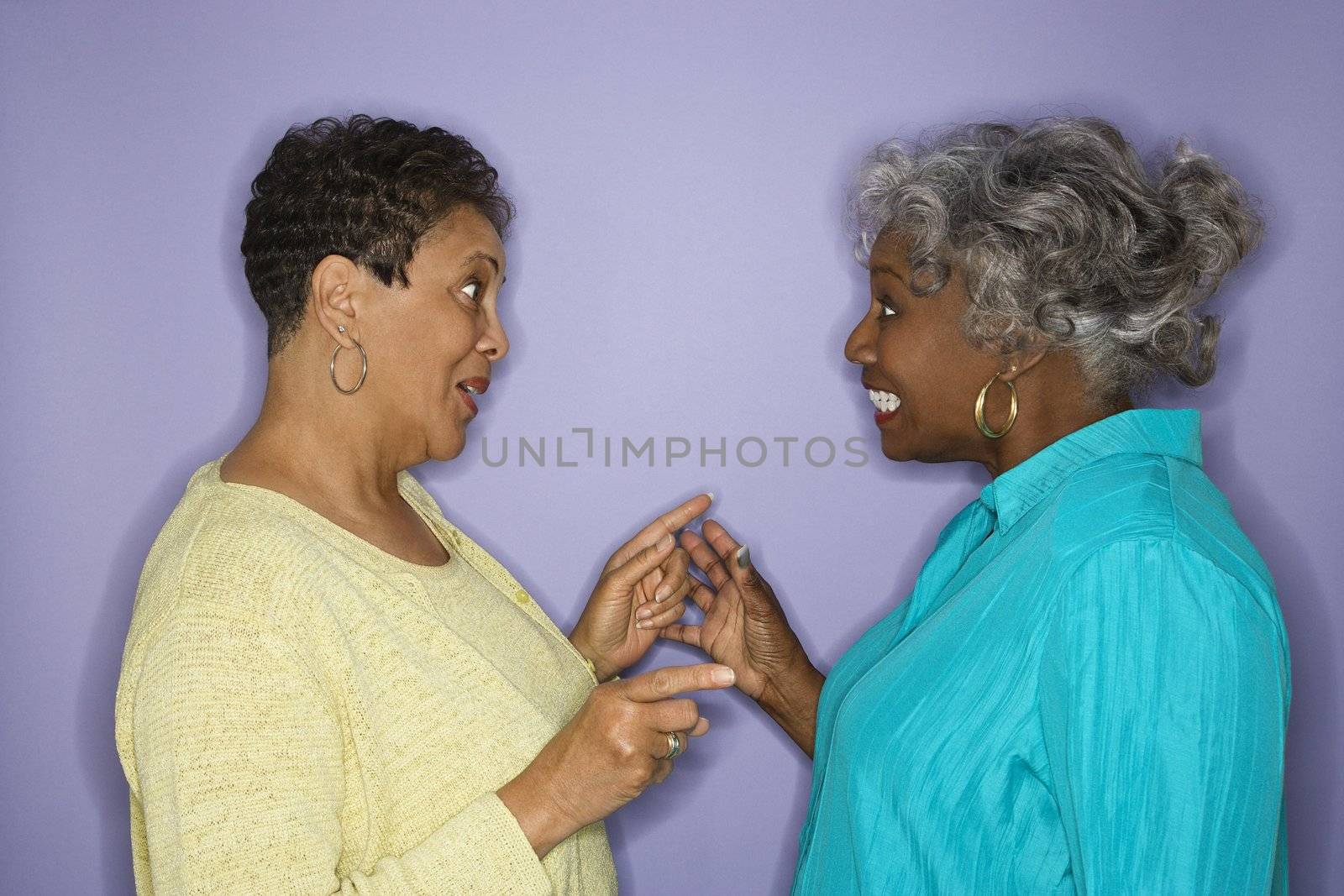 Mature adult African American female pointing at eachother.