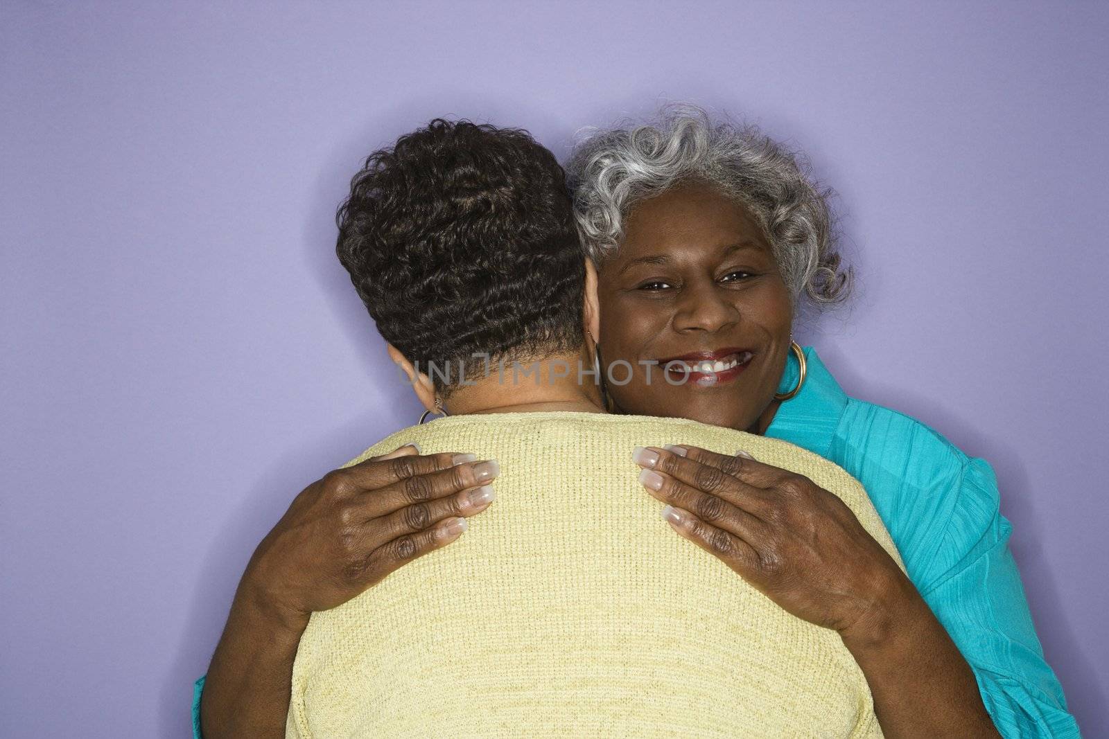 Mature adult African American females embracing.