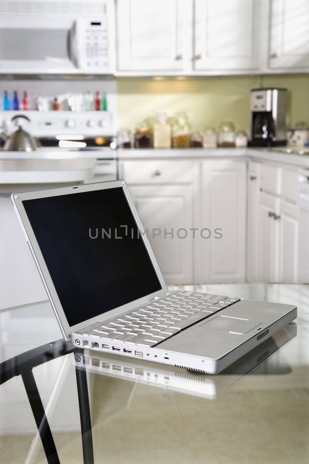 Open laptop computer on top of glass top kitchen table.