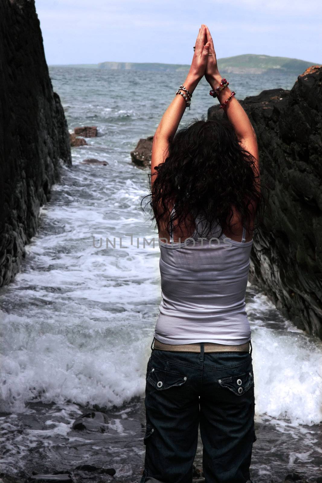 a beautiful woman practicing her yoga on the rocks in a ravine as the waves roll in