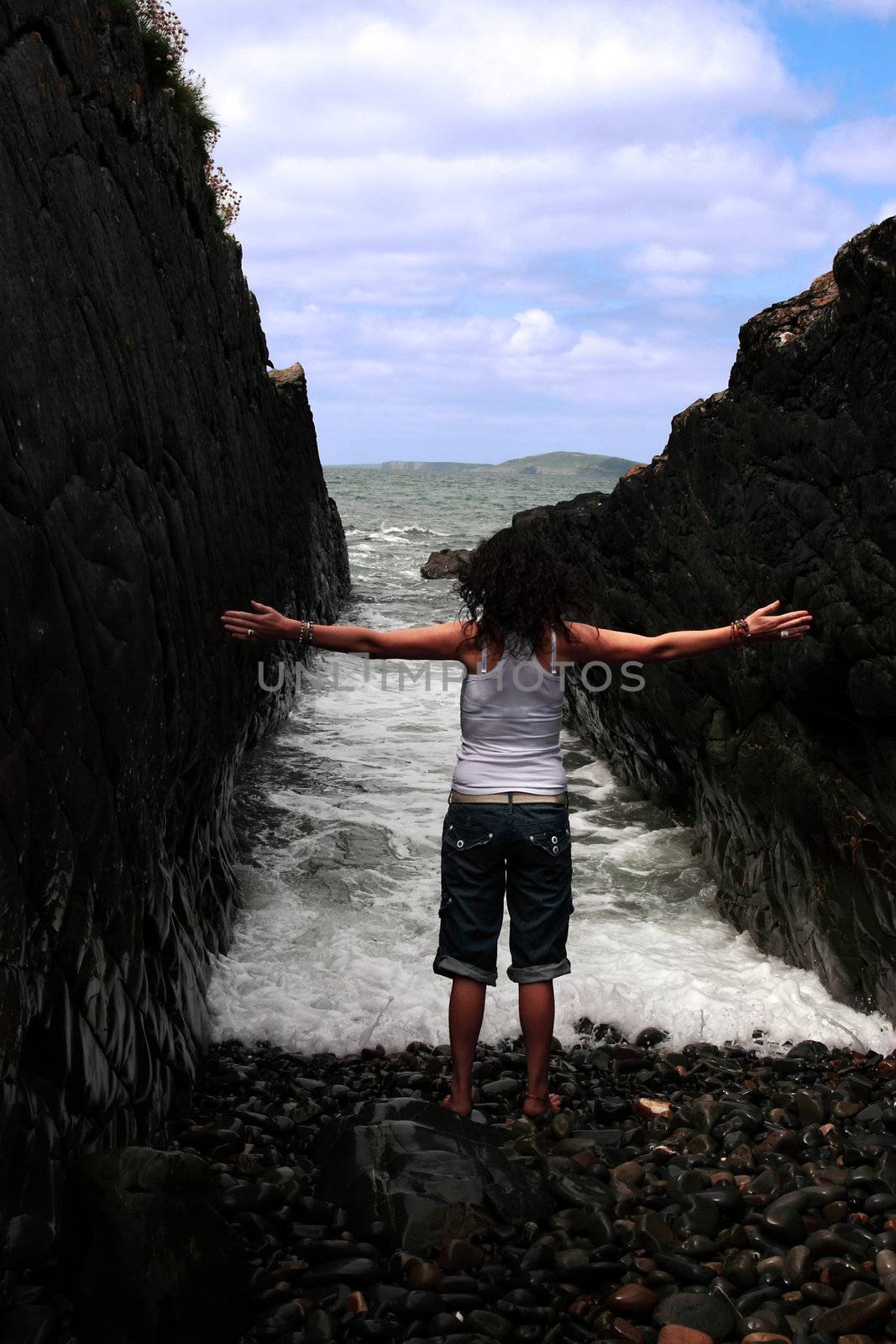 a beautiful woman practicing her yoga on the rocks in a ravine as the waves roll in