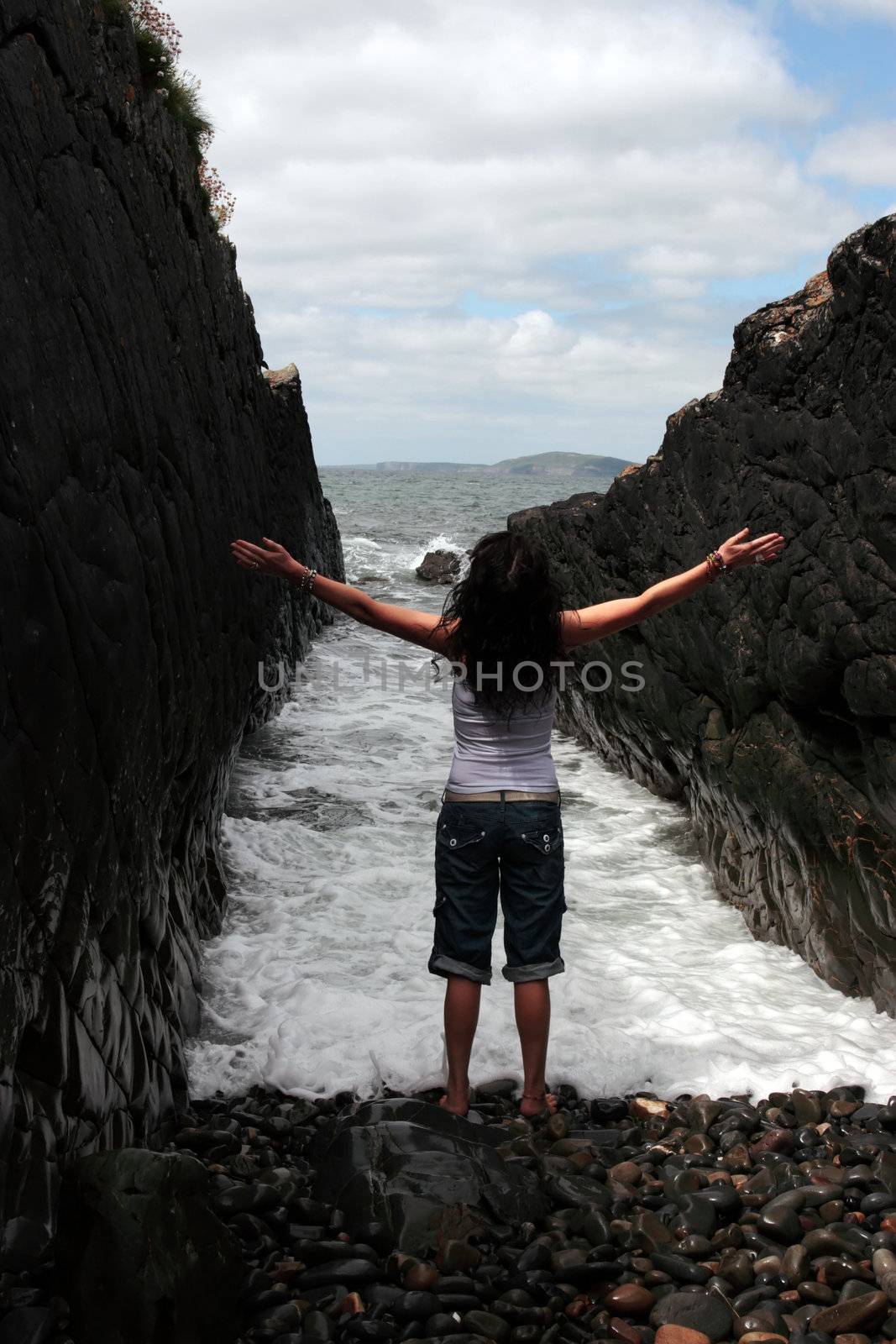 a beautiful woman practicing her yoga on the rocks in a ravine as the waves roll in