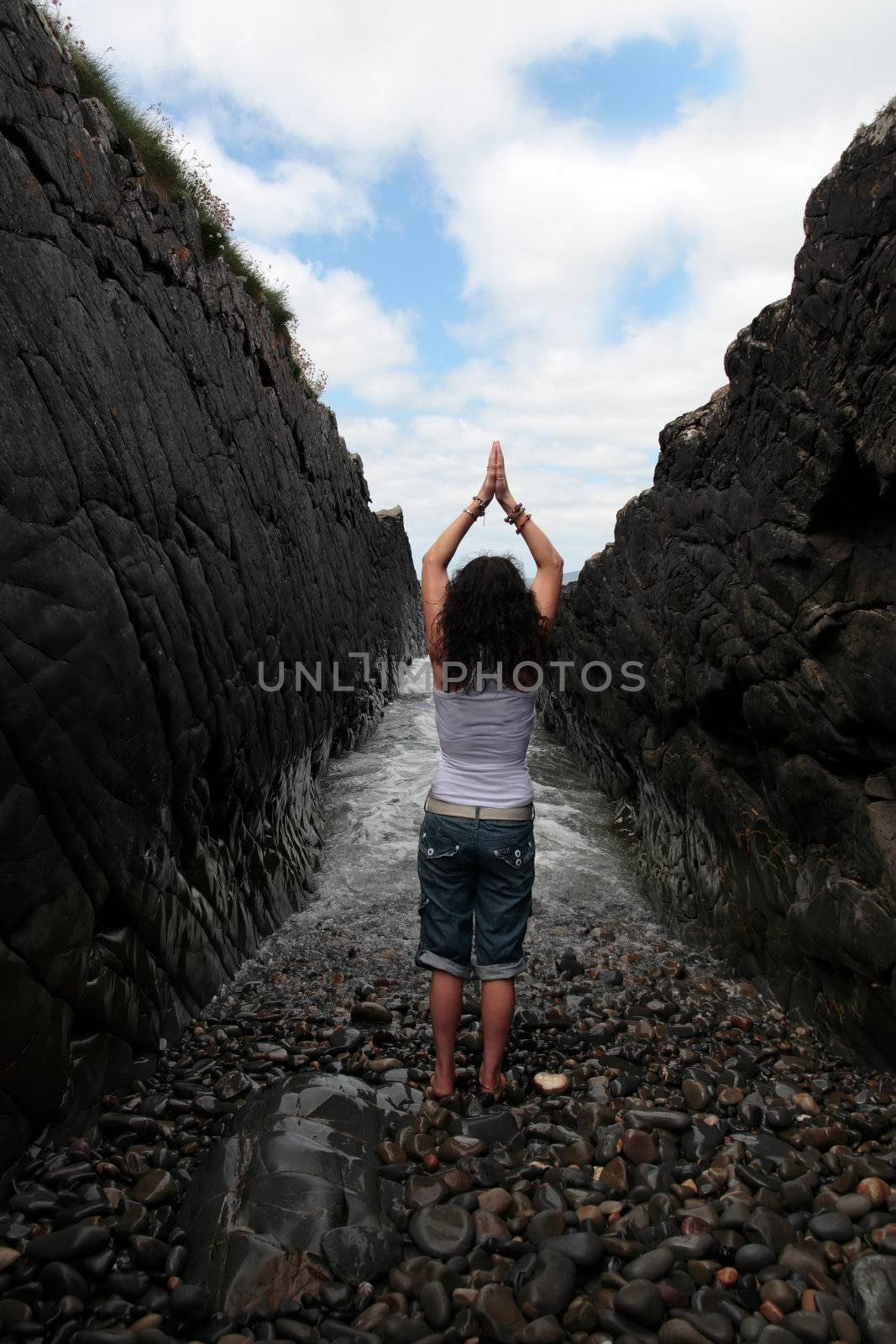 a beautiful woman practicing her yoga on the rocks in a ravine as the waves roll in