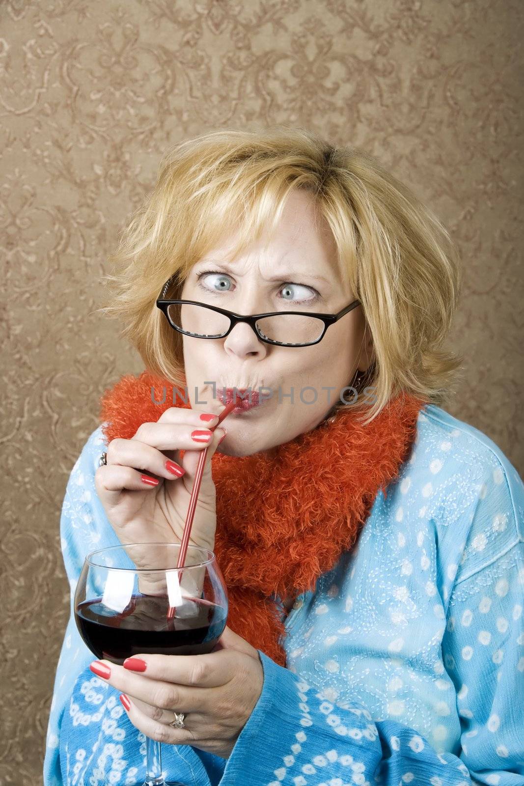 Crazy woman with crossed eyes drinking wine through a straw