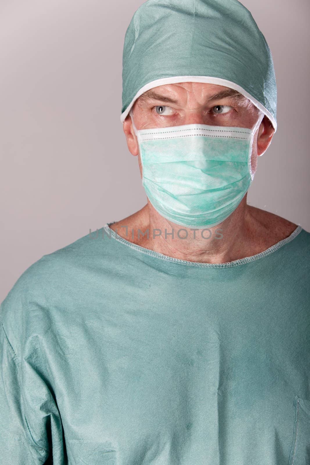 A 60 year old surgeon on a gray background.