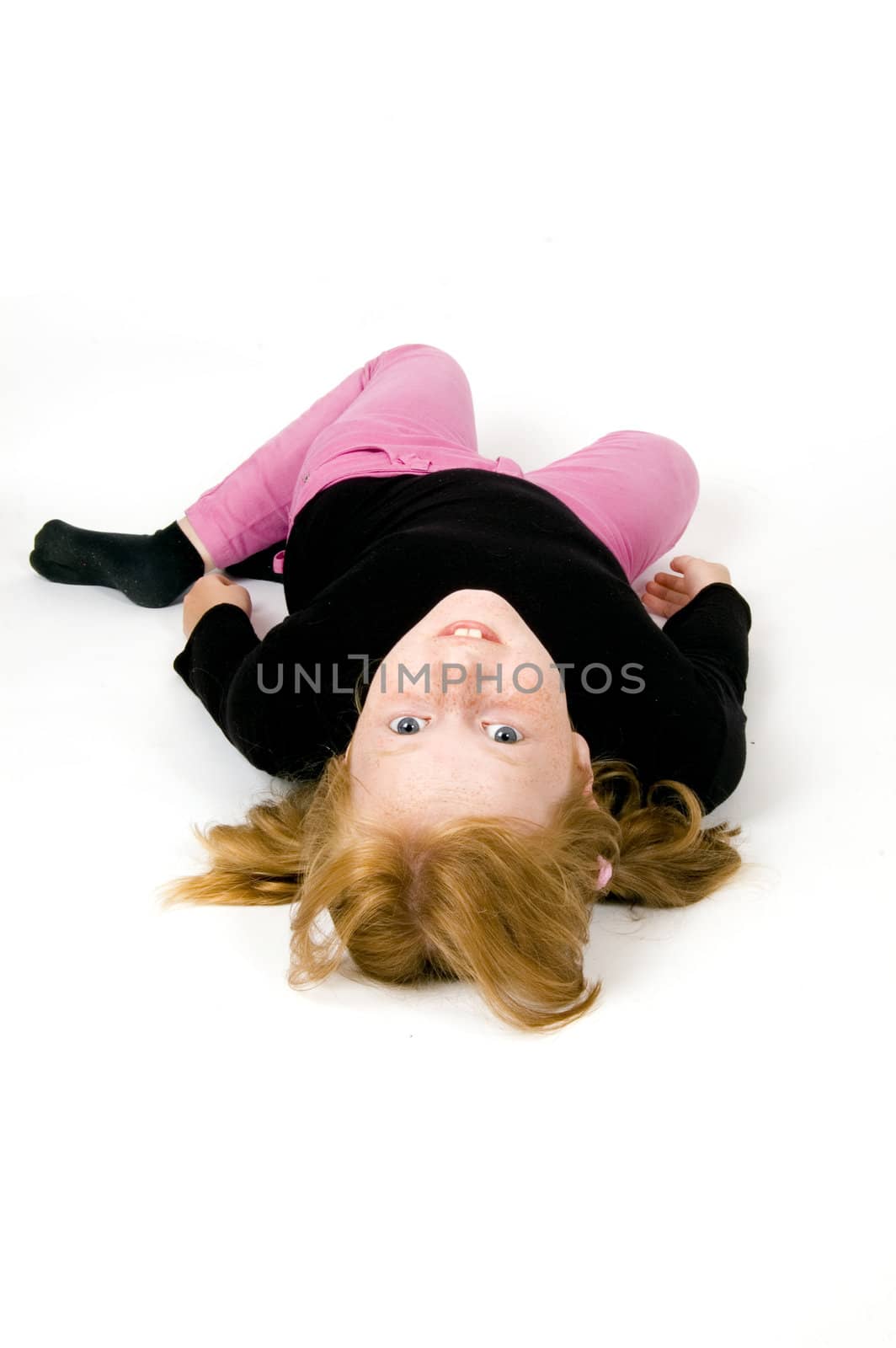 little girl is laying on floor looking towards the camera
