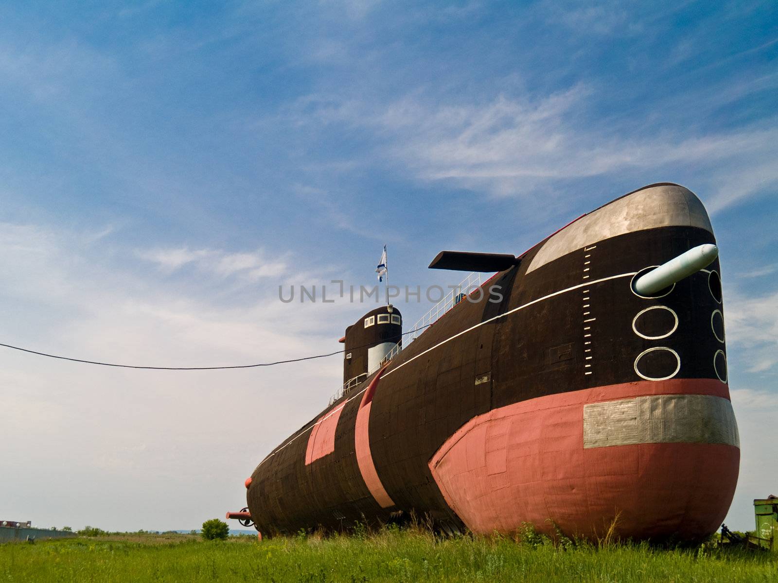 Surreal image of old steel submarine on a green field
