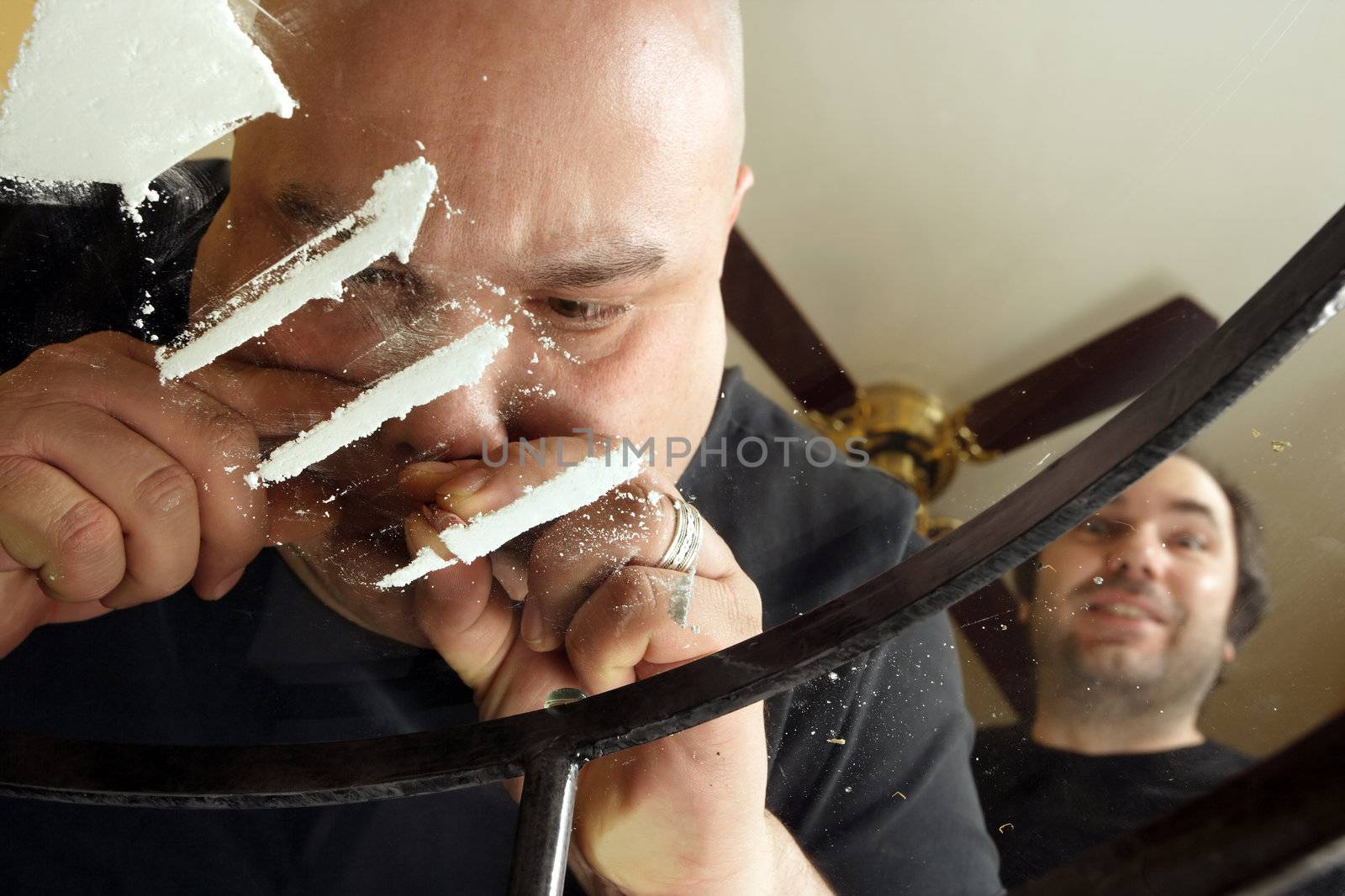 An Image of drug abuse. Male snorting lines of cocaine on a dirty glass table while another waits his turn.  View from underneath and through the glass.
