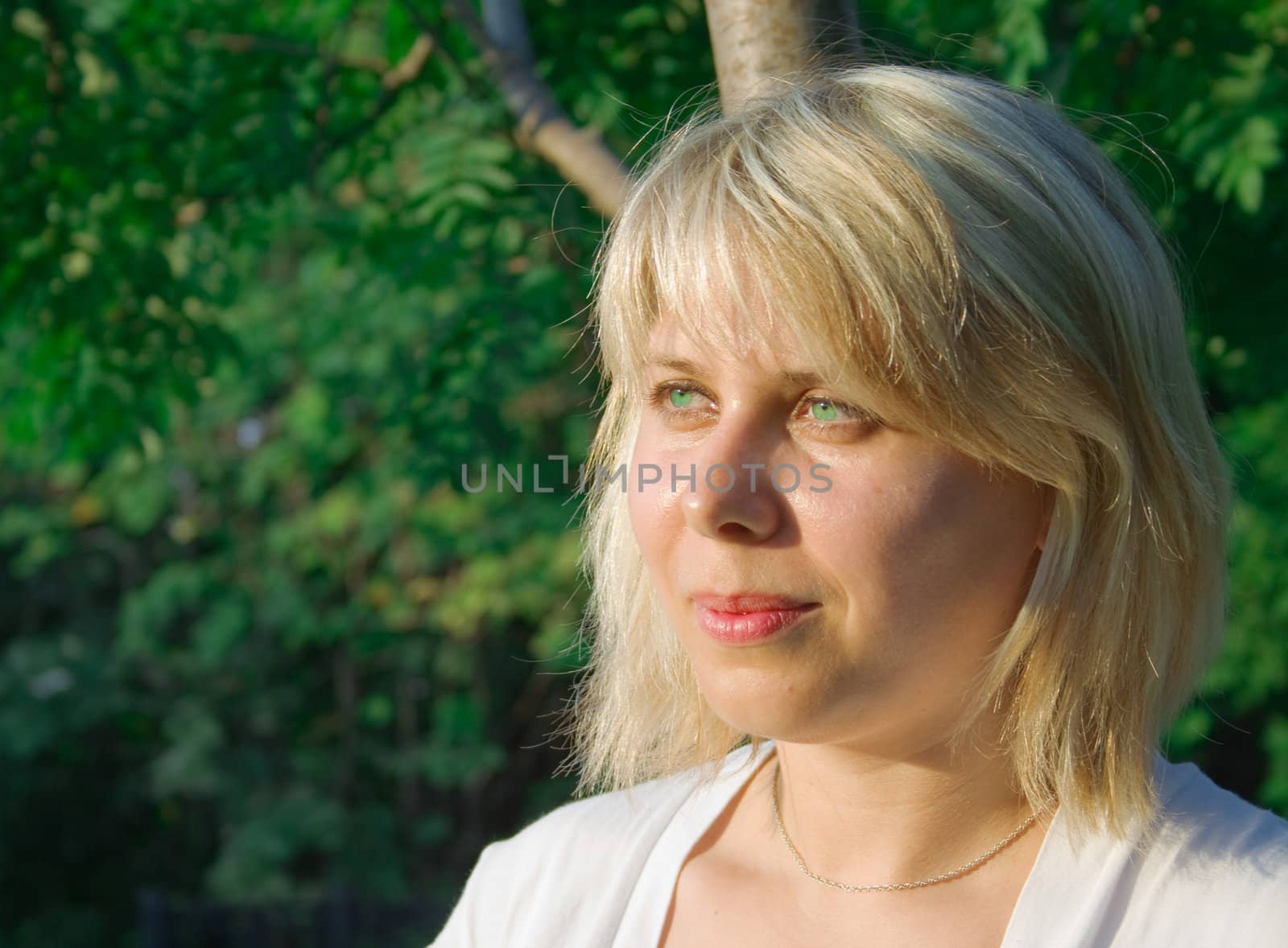 Portrait of the happy beautiful young woman-blonde against trees