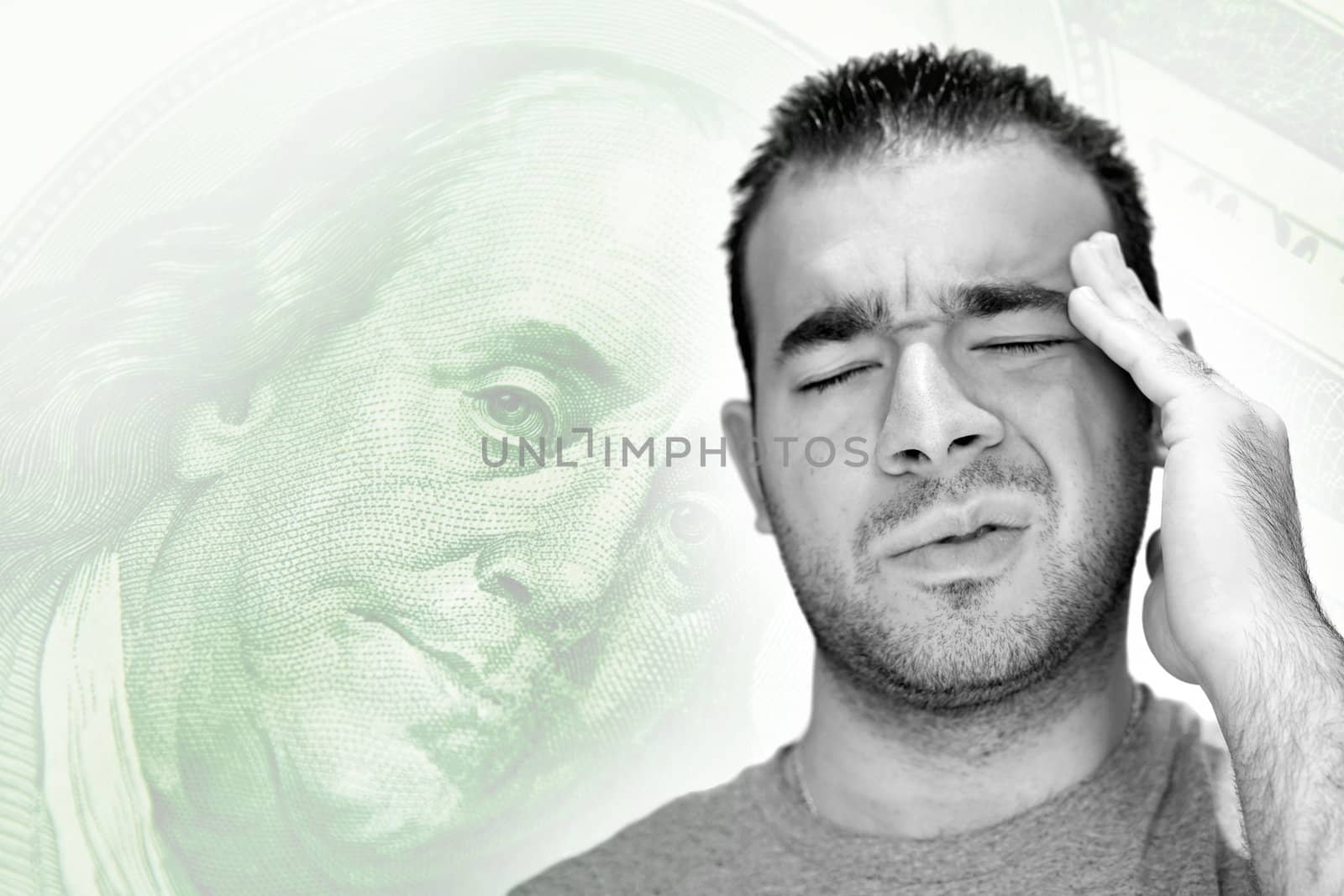A young man holds his head in anguish as he thinks about his money problems with either debt or unemployment.