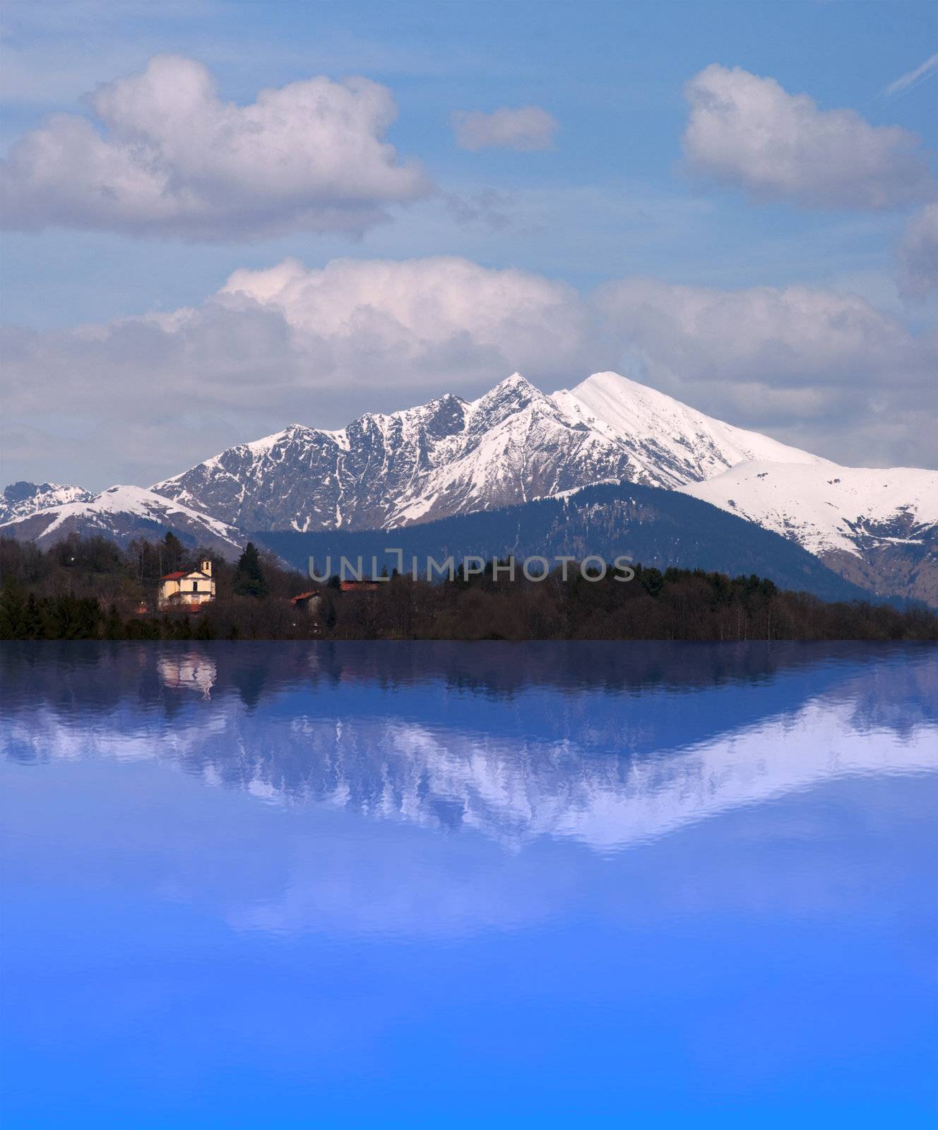 A snow-covered mountain with a church reflected in a lake