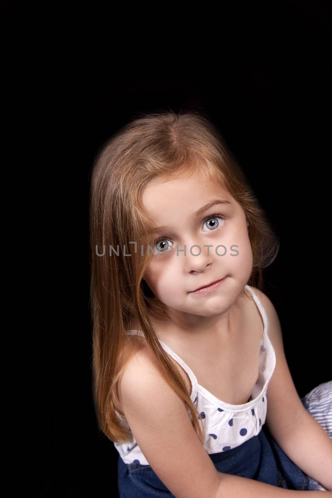 Unhappy young girl with downturned smile against black