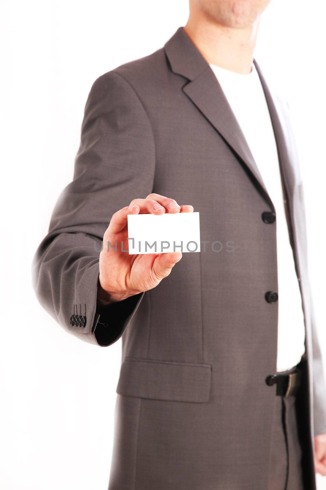 A business man holding his unmarked business card into the camera. The body of a man is seen blurred in the background.