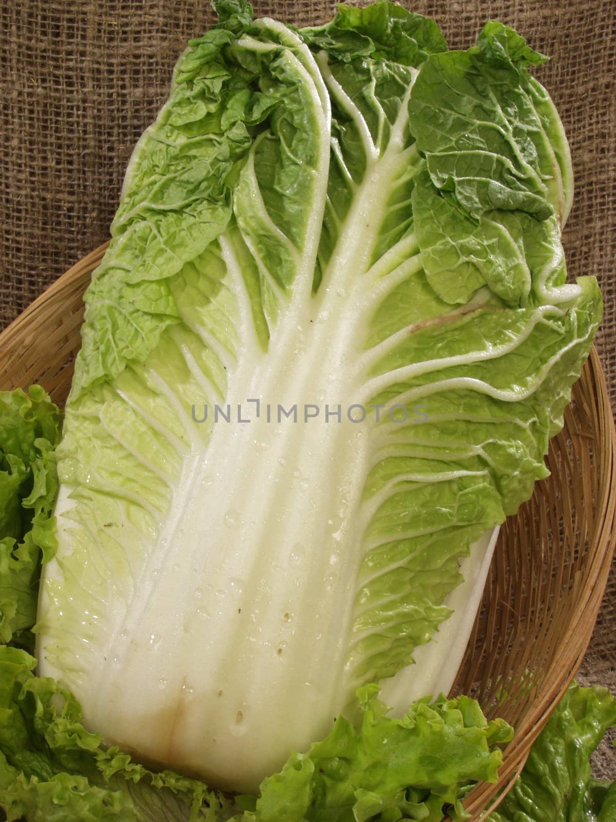 Chinese cabbage with leaves of salad in a basket on a sacking