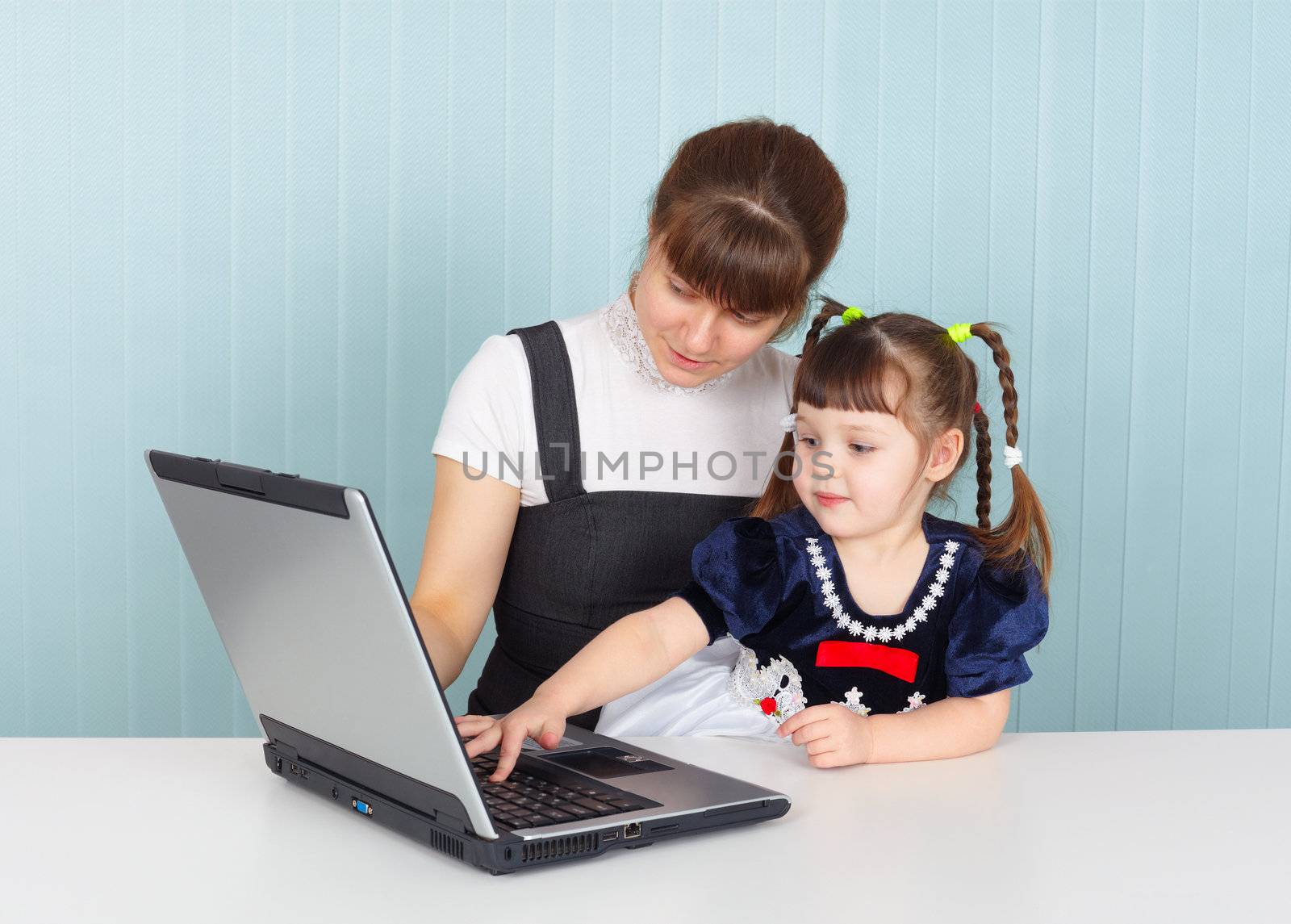 Mother and daughter sitting at table with a laptop