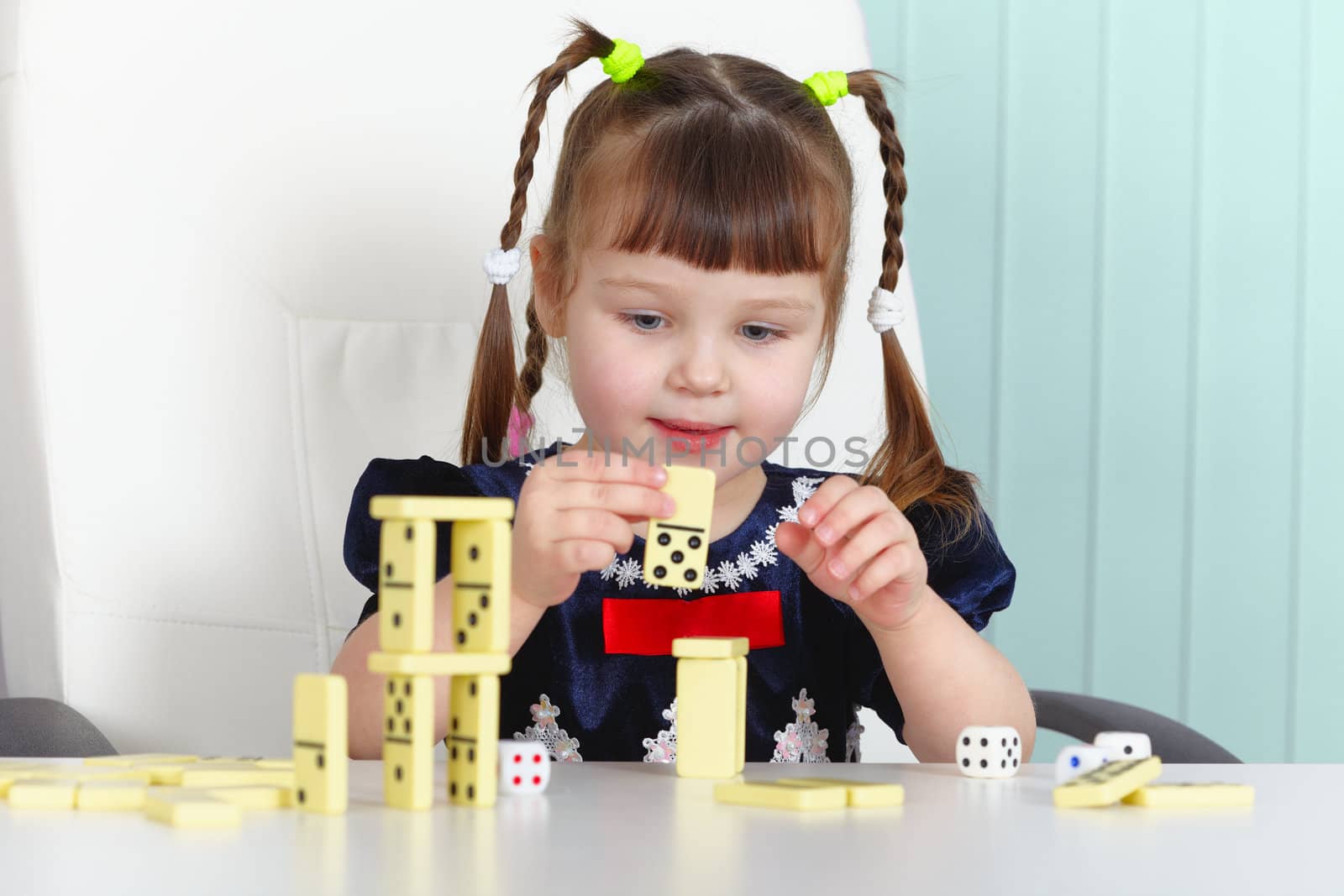 A child playing with dominoes sitting at the table