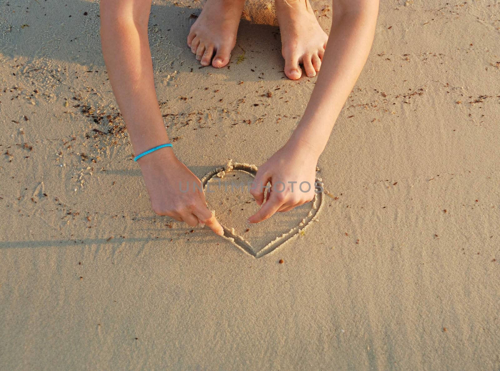 a girl is drawing hearts in a sand