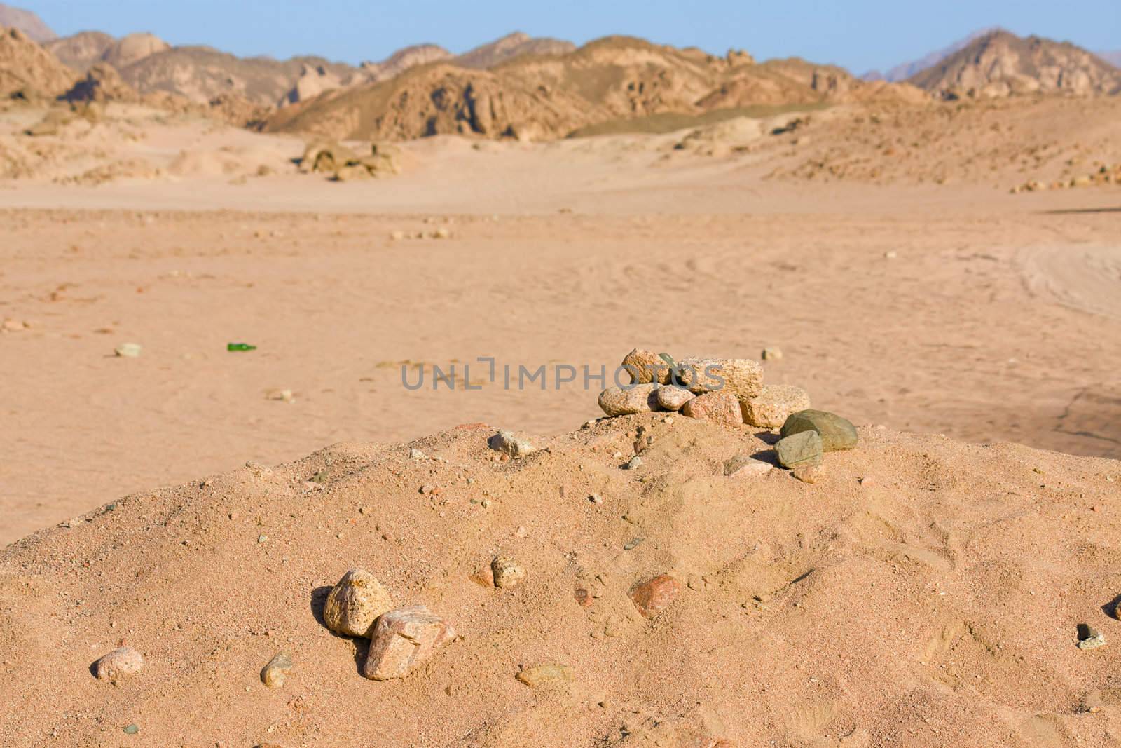 Egypt, the desert. On the background of mountains and blue sky on the sand are the stones.