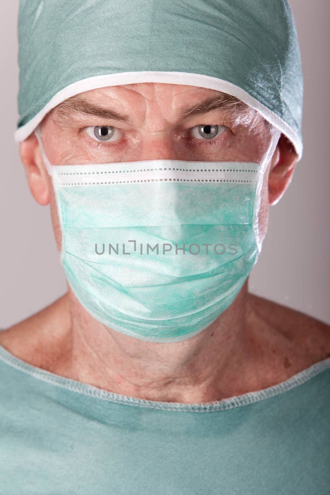 A 60 year old surgeon on a gray background.