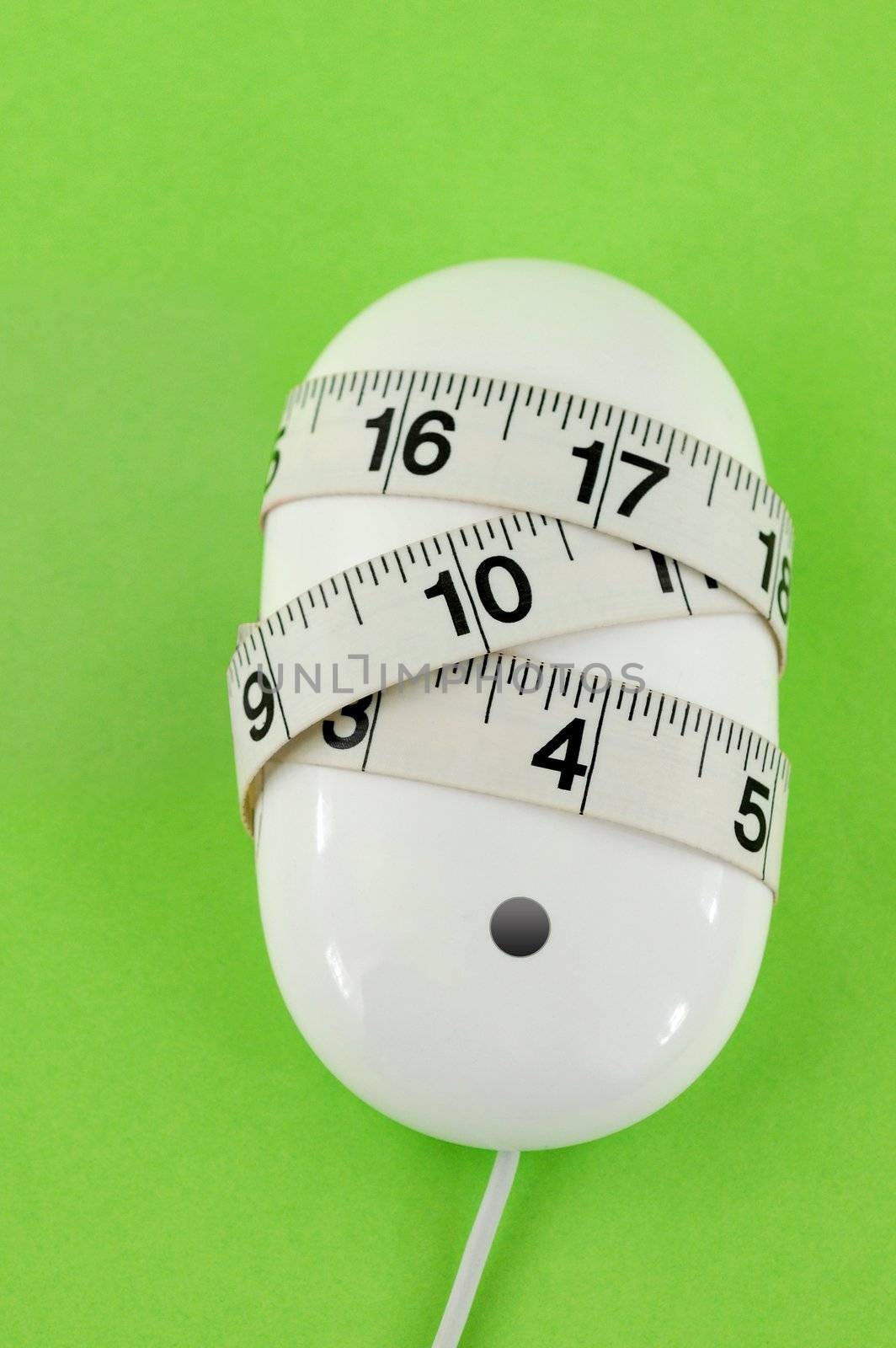 White computer mouse with measuring tape wrapped round it. Green paper background.