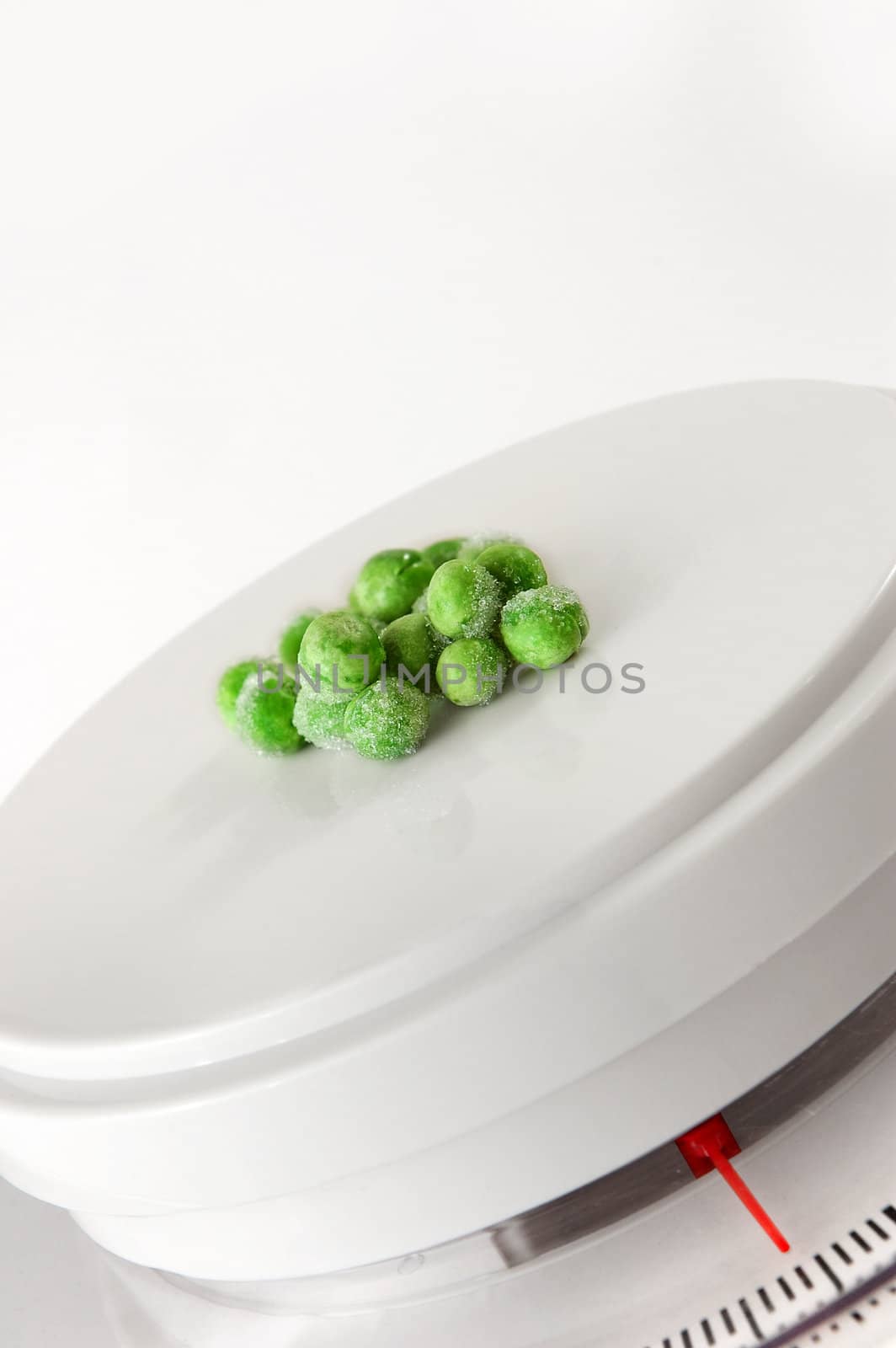 Frozen peas on weighing scale by maggiemolloy