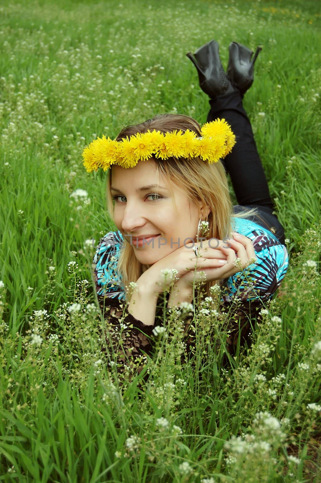 beautiful girl with dandelion diadem lying in grass