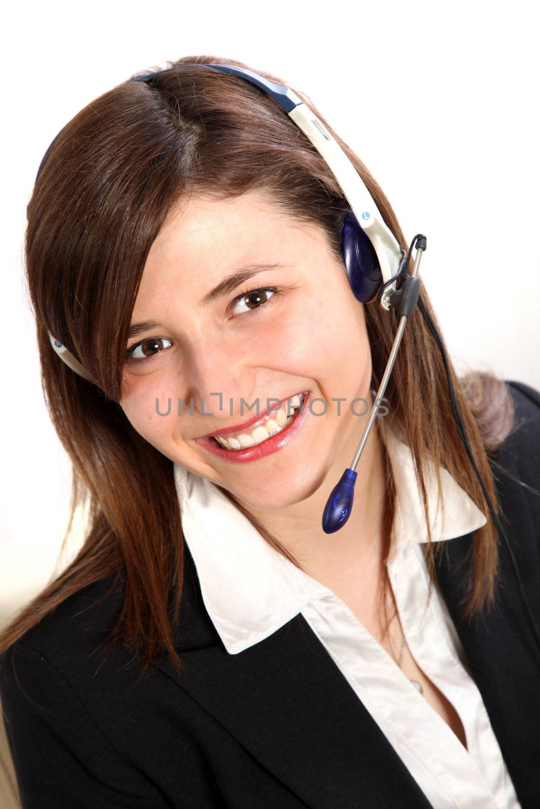 Young Woman in a call center. She wears a headset and smiles toward the camera