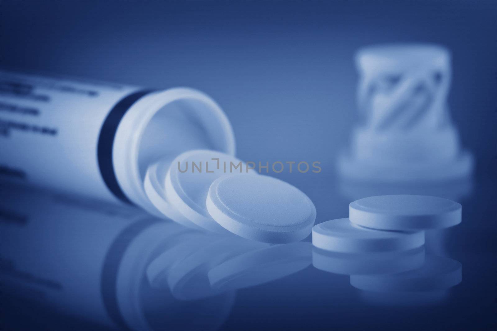 close up of open bottle with few pills out. Syallow DOF. Blue toning