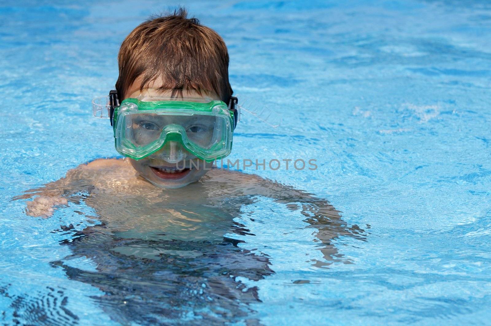 a young boy in pool with goggles on