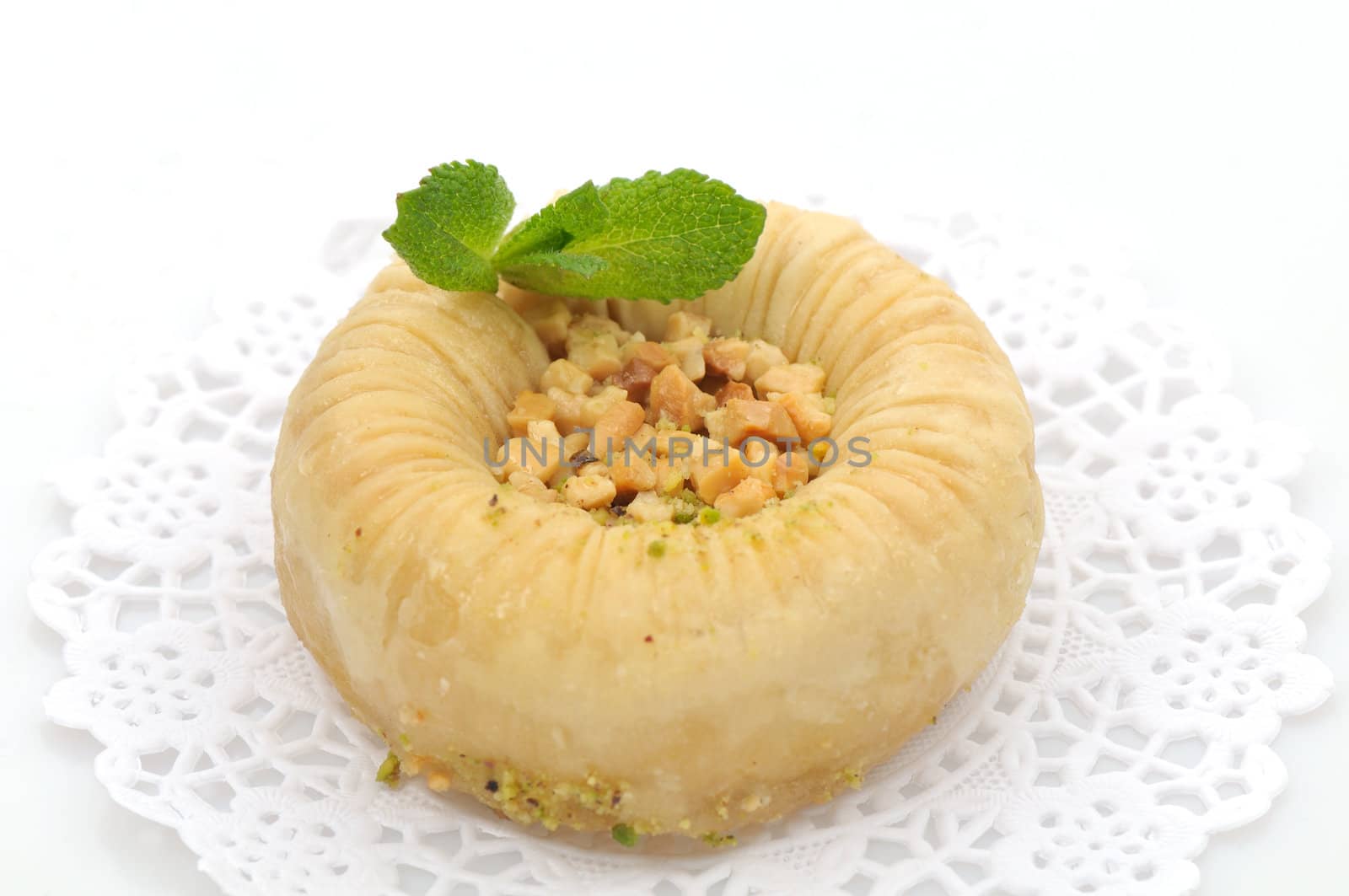 Fresh round baklava on a white paper doily, decorated with mint leaves