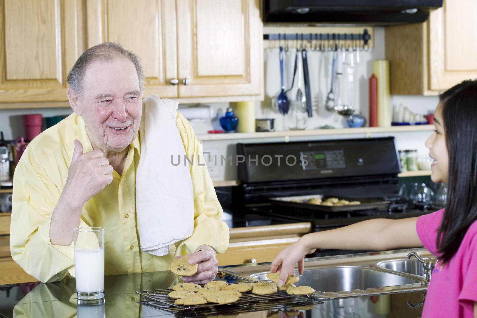 Elderly man sharing cookies with granddaughter