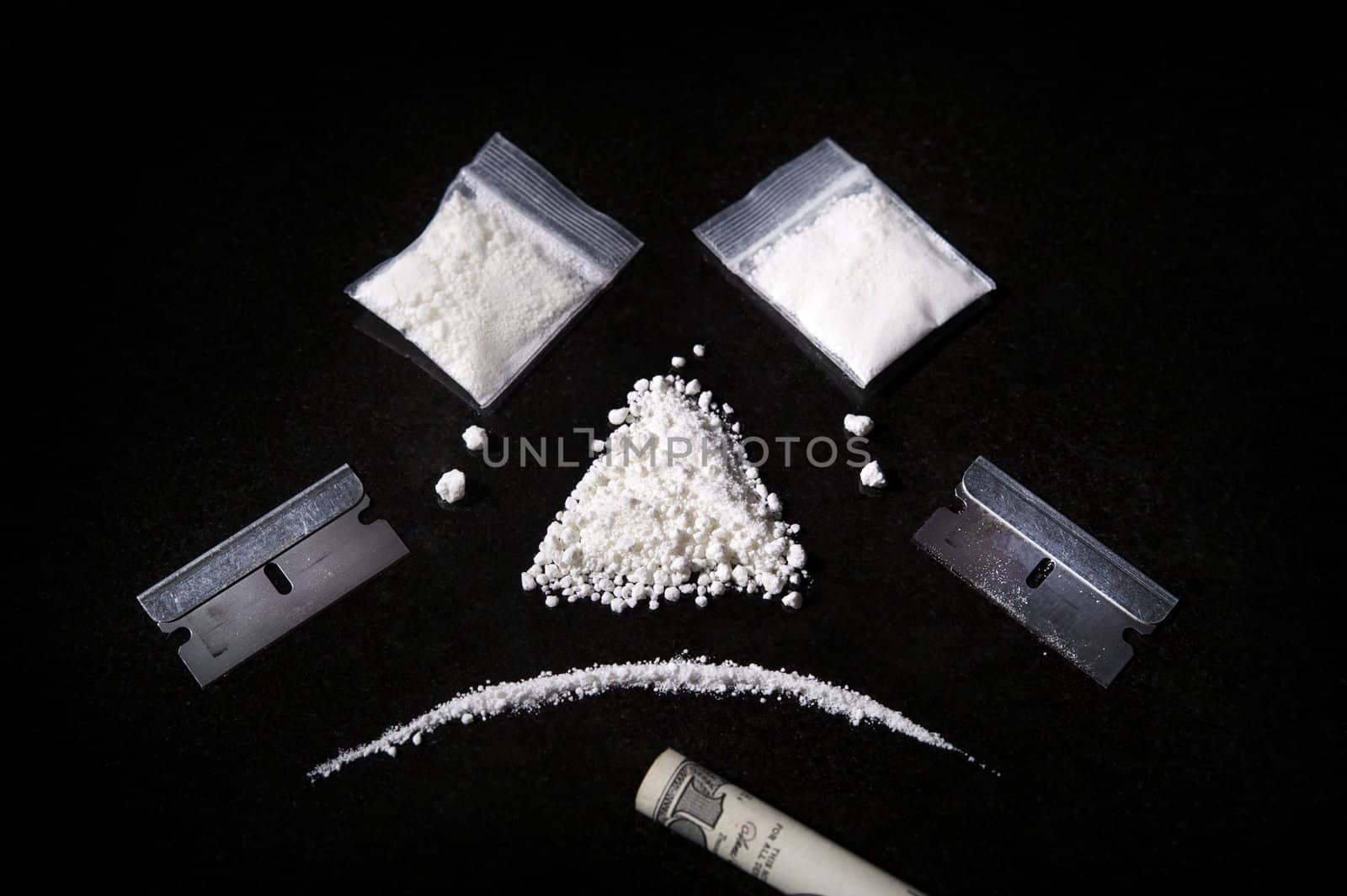 Image of a composition of cocaine, razor and rolled bill,  making a sad face