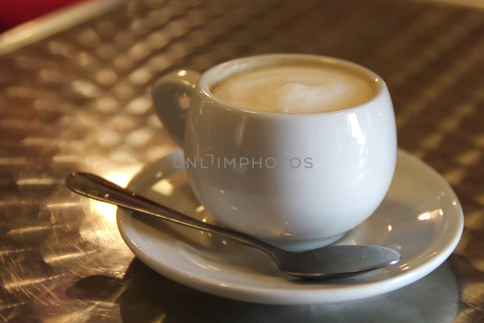 Cup of cappuccino coffee and spoon on a cafe table