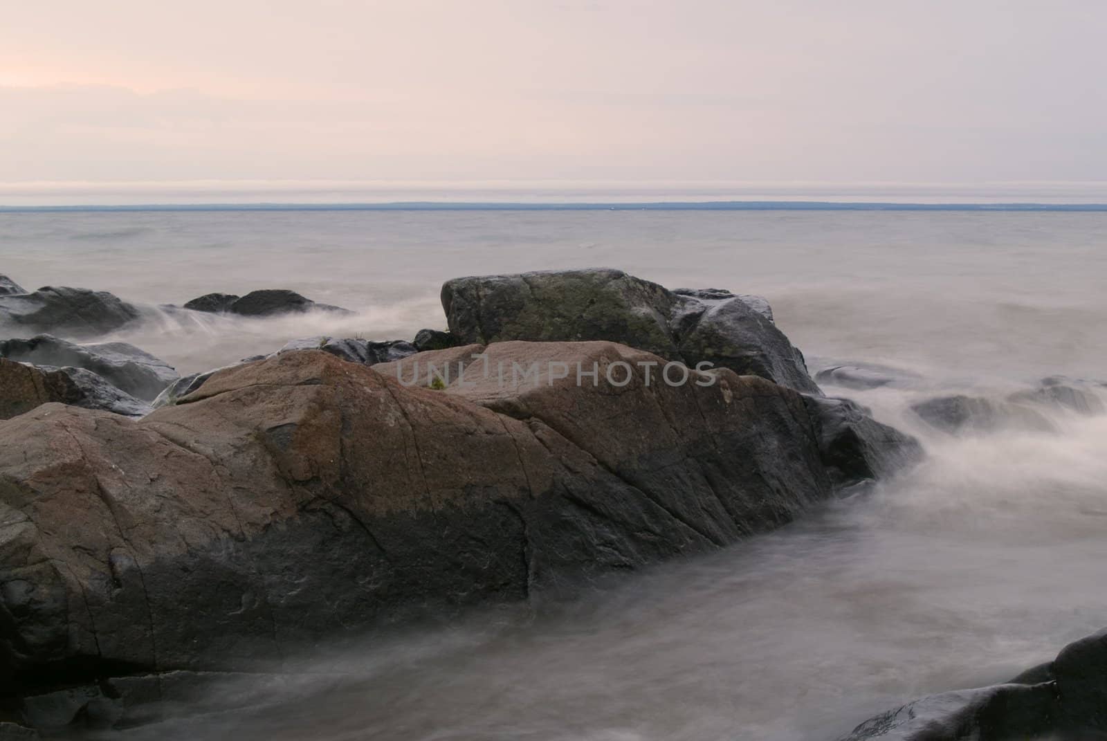 Stones in stormy and misty grey water on Lake Superior.